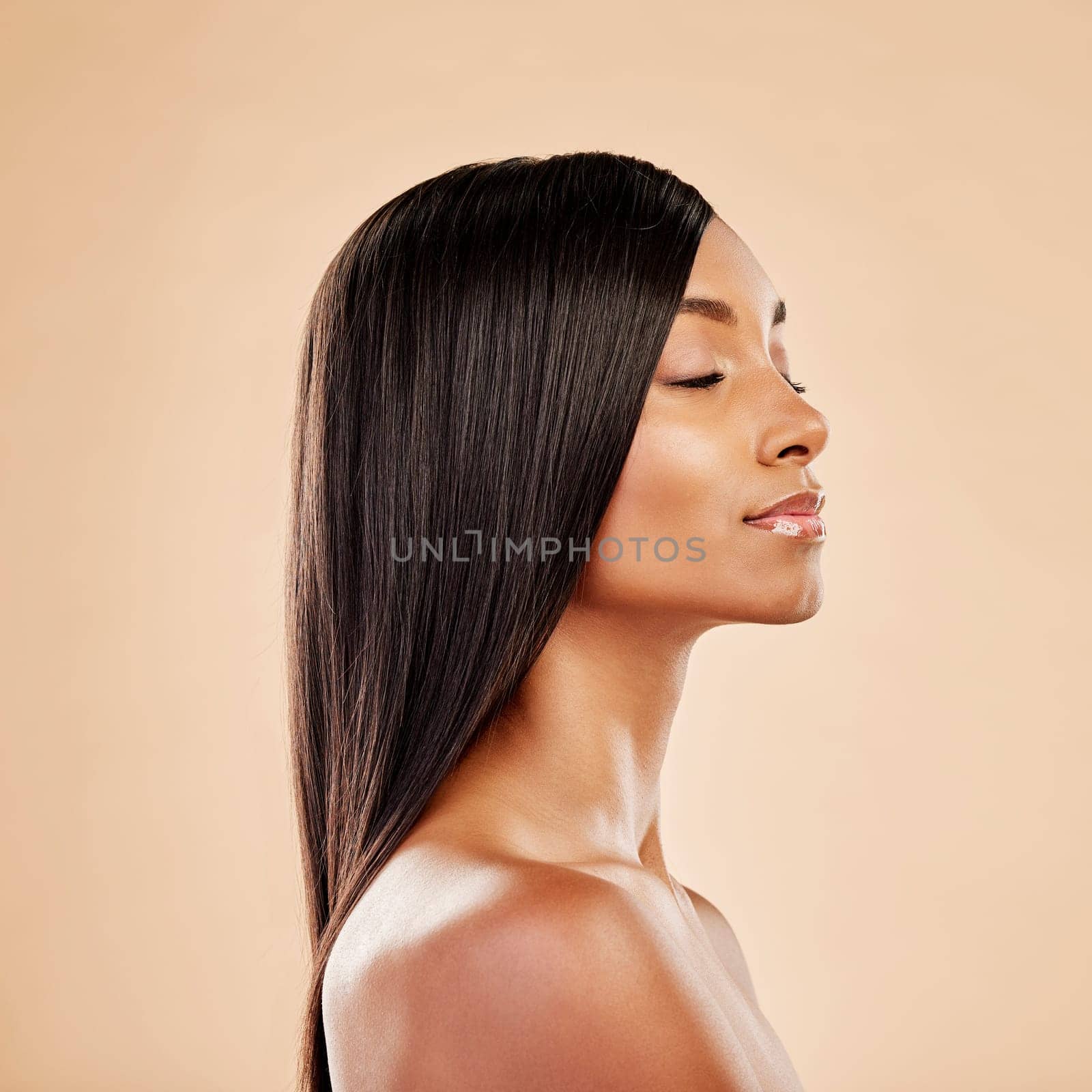 Beauty, hair care and profile of a woman in studio with natural glow and shine. Hairstyle, cosmetics and wellness of Indian person for hairdresser, makeup or salon results on a beige background.