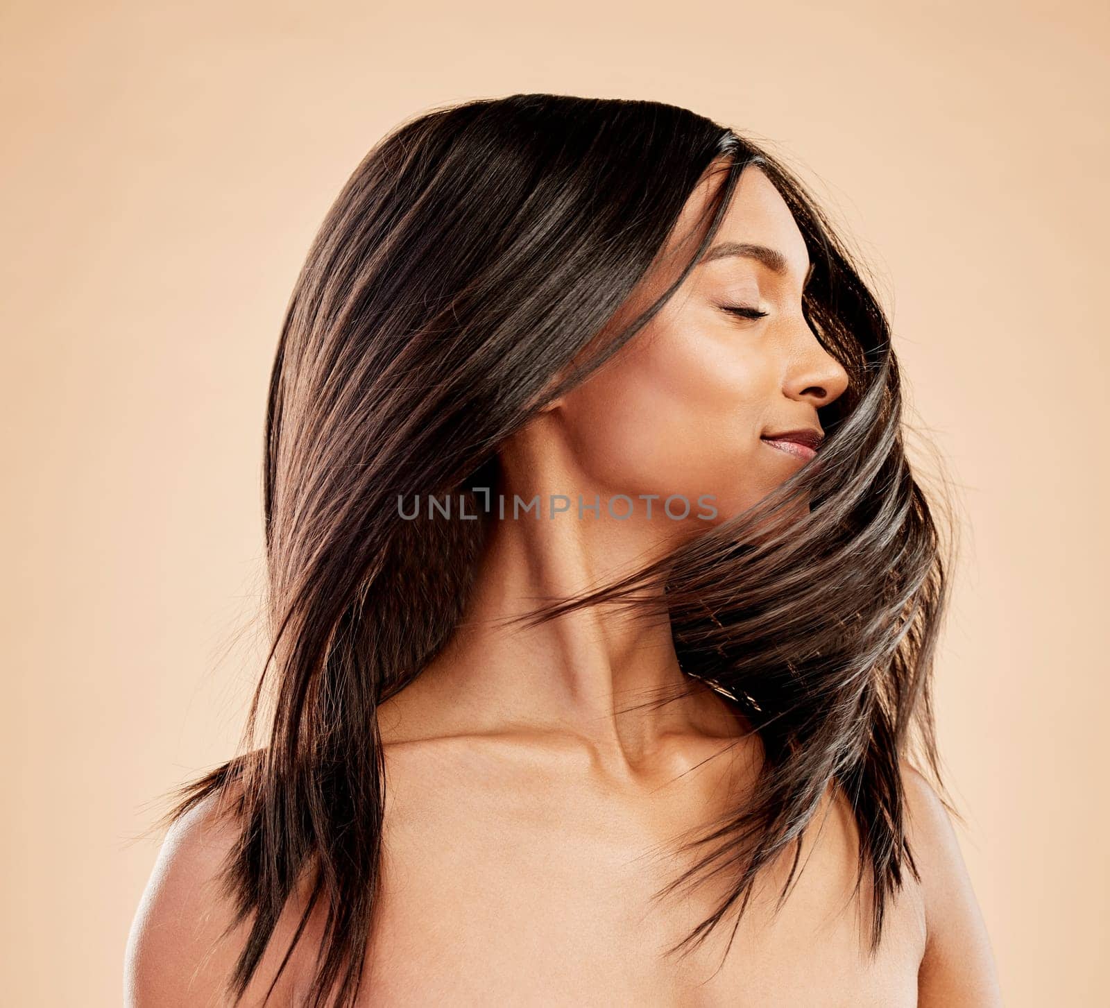 Woman, shaking hair and beauty with shine, growth and texture with natural cosmetics on studio background. Indian female model, satisfied with salon treatment and Brazilian, hairstyle and haircare by YuriArcurs