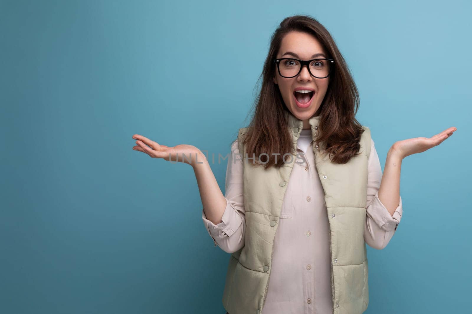 enthusiast smart young brunette woman in casual look with eyeglasses on studio background.