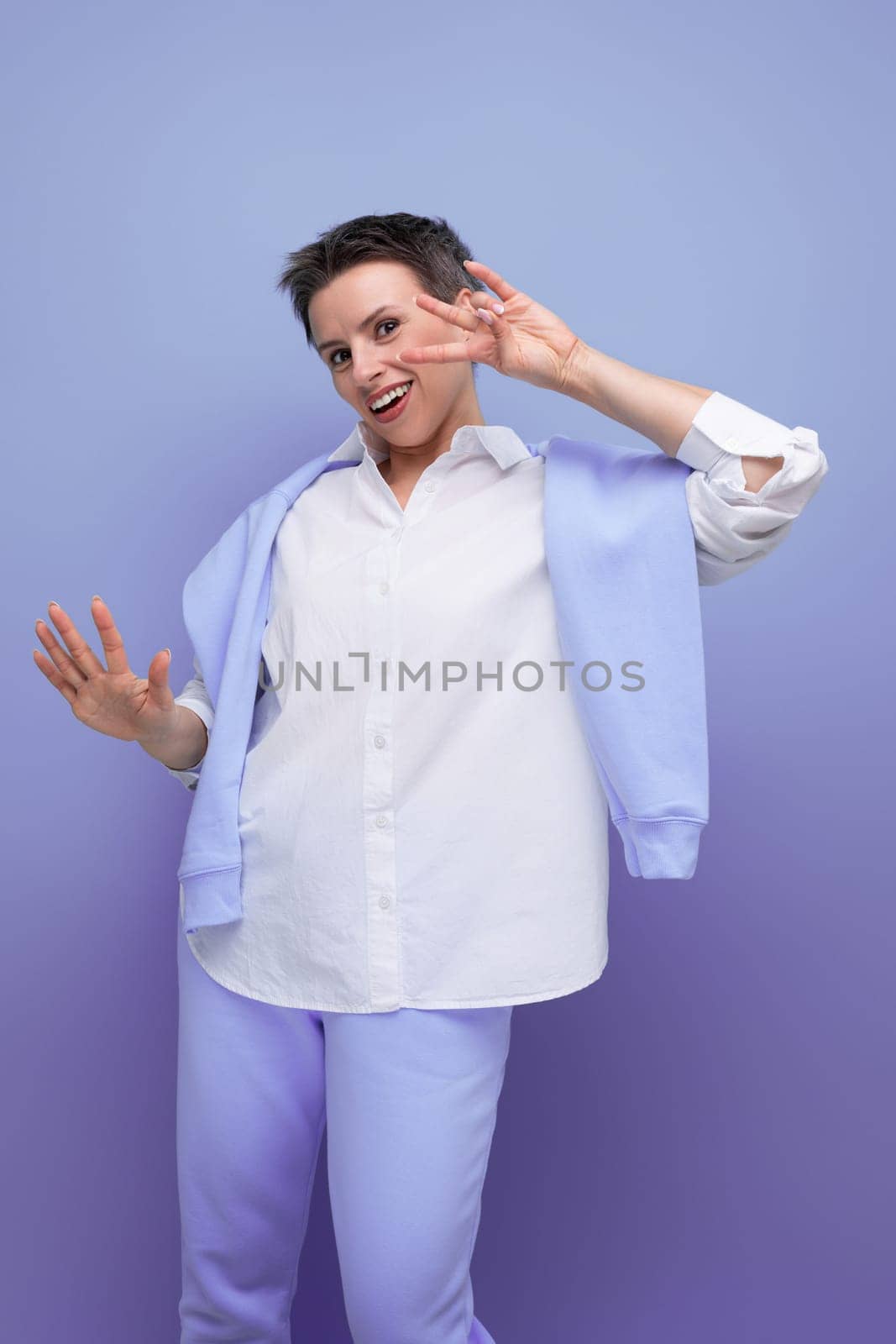 vertical photo of a stylish fashionable young lady with tousled hair in a white shirt in an informal setting.