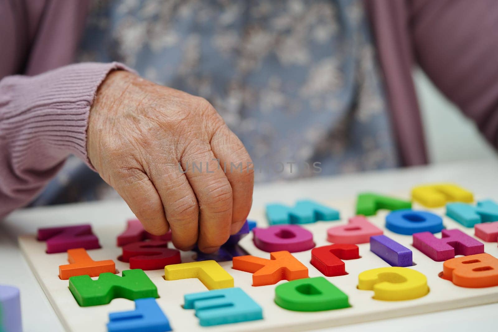 Asian elderly woman playing puzzles game to practice brain training for dementia prevention, Alzheimer disease. by sweettomato