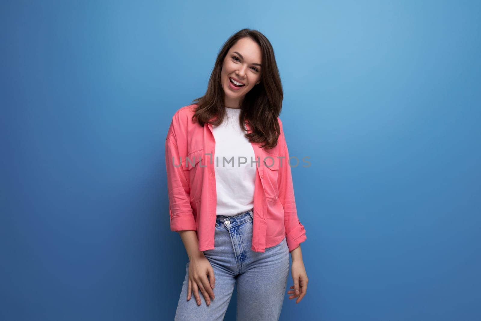 well-groomed european brunette 30s woman in pink shirt on studio background.