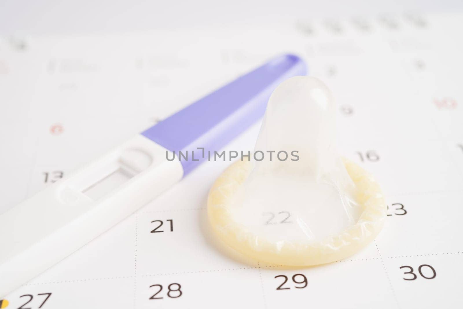 Pregnancy test and condom for female on calendar, ovulation day.