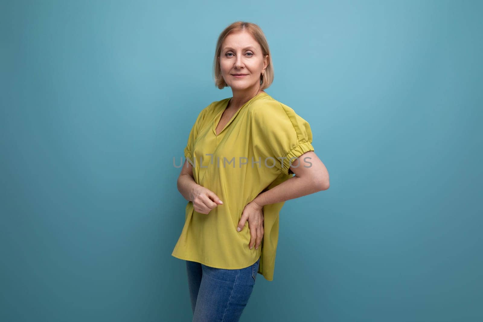 attractive 50s blonde woman in yellow t-shirt posing.