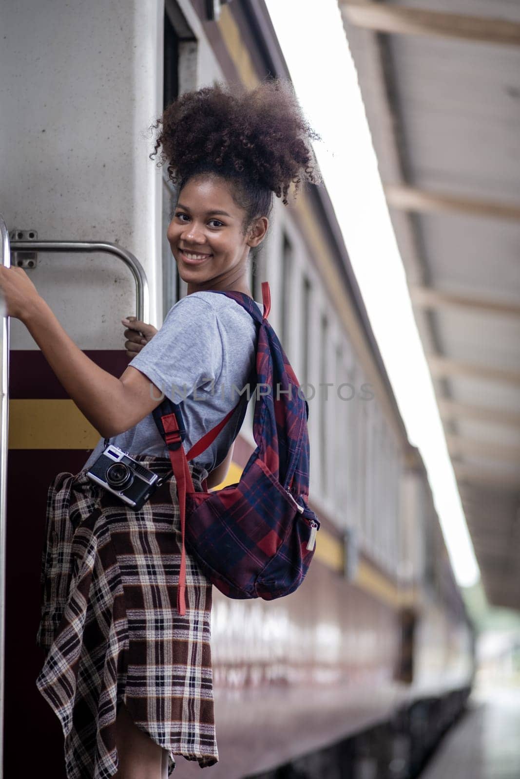 Traveler African Asian American woman getting in a train to hop on train, Young woman female standing on train door peeking out looking from door, tourist on a train station. High quality photo