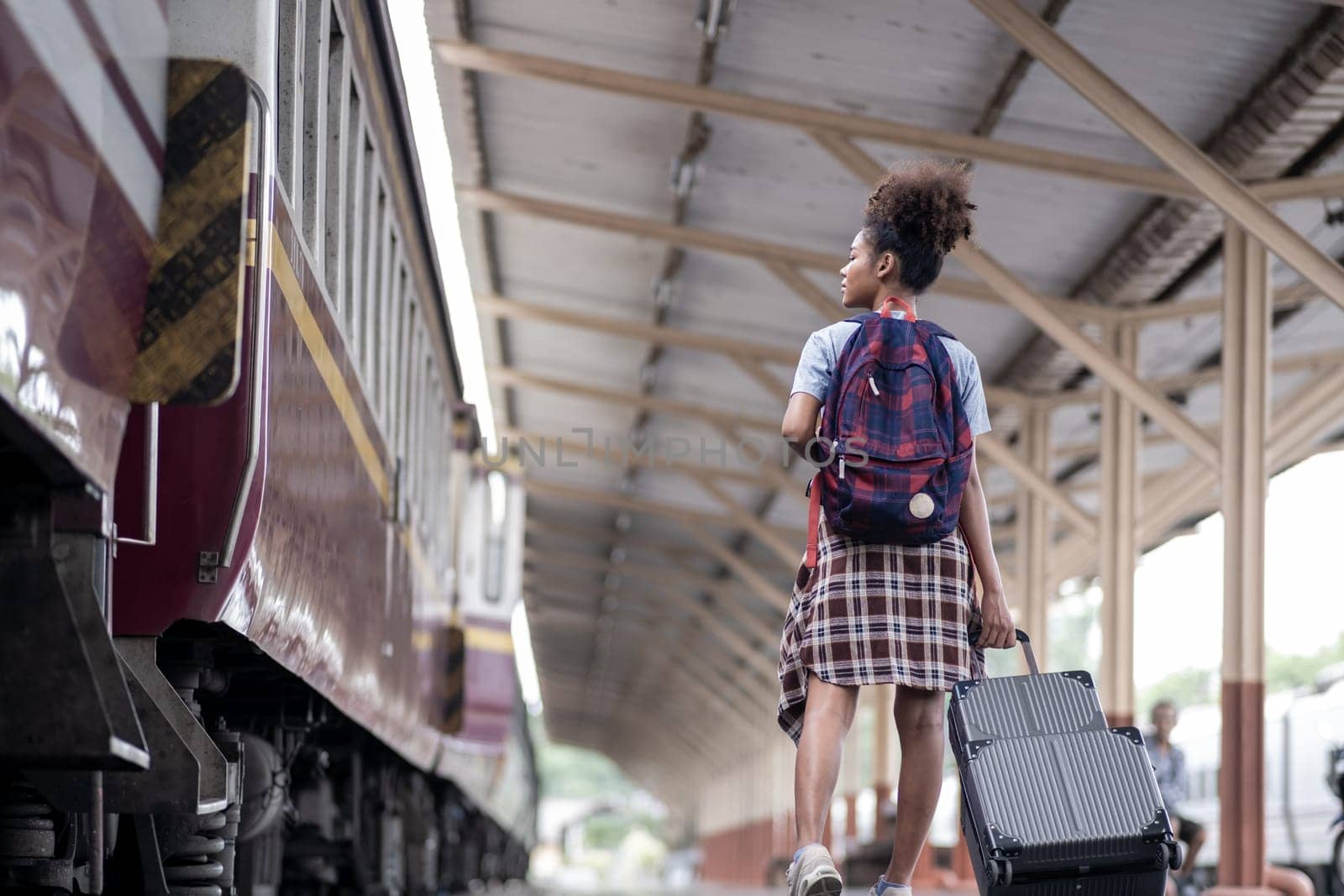 Young female traveler walking standing with a suitcase at train station. woman traveler tourist walking standing smiling by wuttichaicci