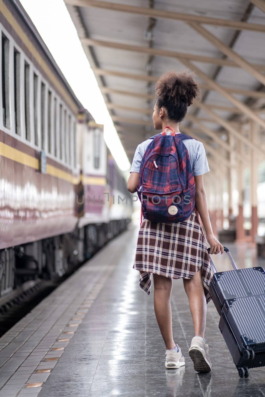 Young female traveler walking standing with a suitcase at train station. woman traveler tourist walking standing smiling with luggage at train station. High quality photo