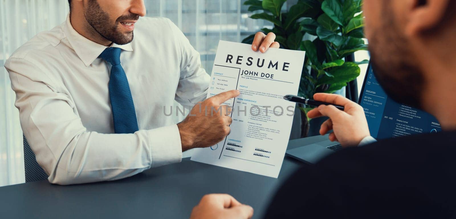 Interviewing job applicant in office with resume paper. Candidate wear suit for formal conversation with interviewer. Recruitment process with question about career and work experience. Fervent