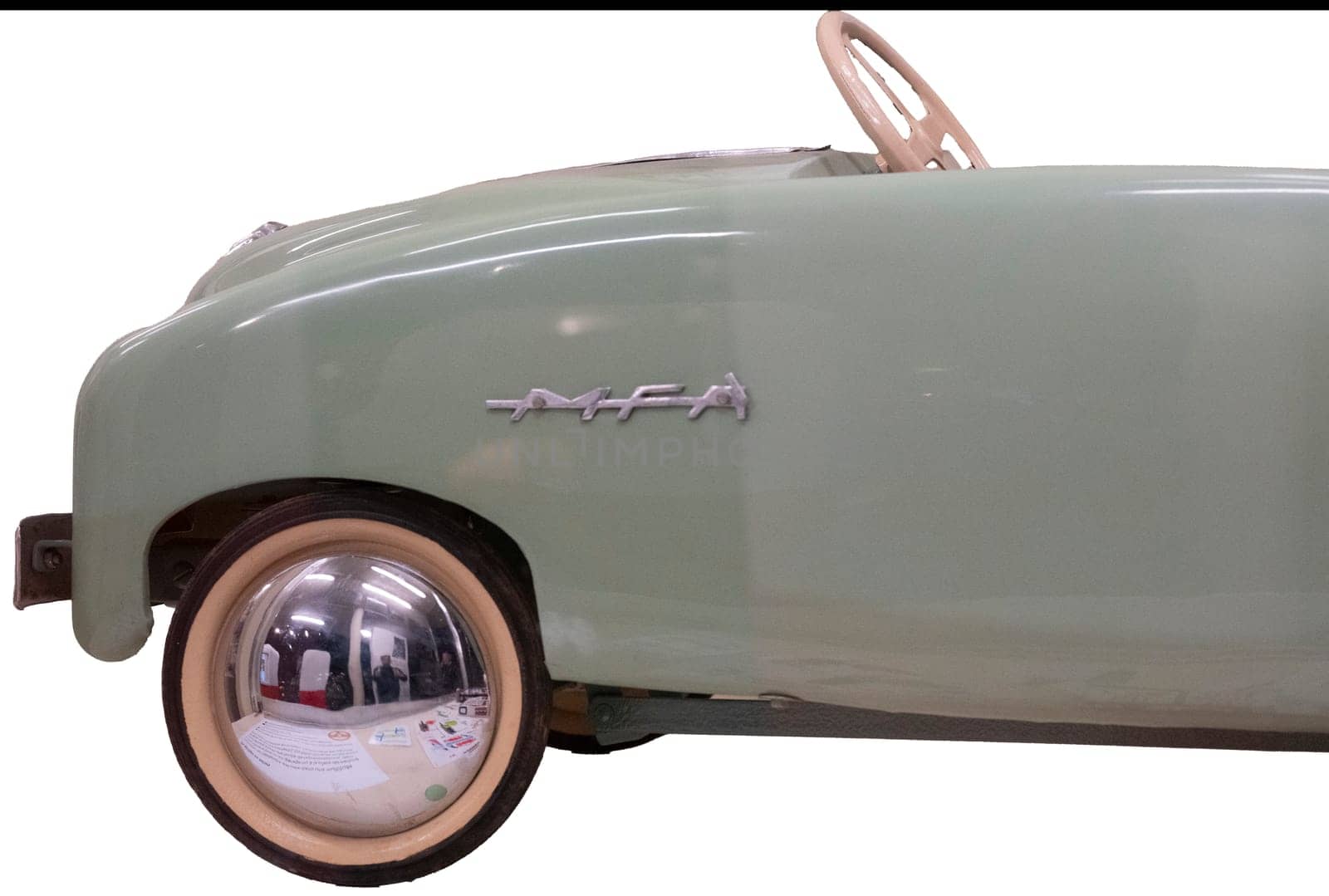 Close up detail of the front end of a mint green MFA pedal car with shiny round hubcaps, a vintage toy for children made in France. Isolated on white with clipping path