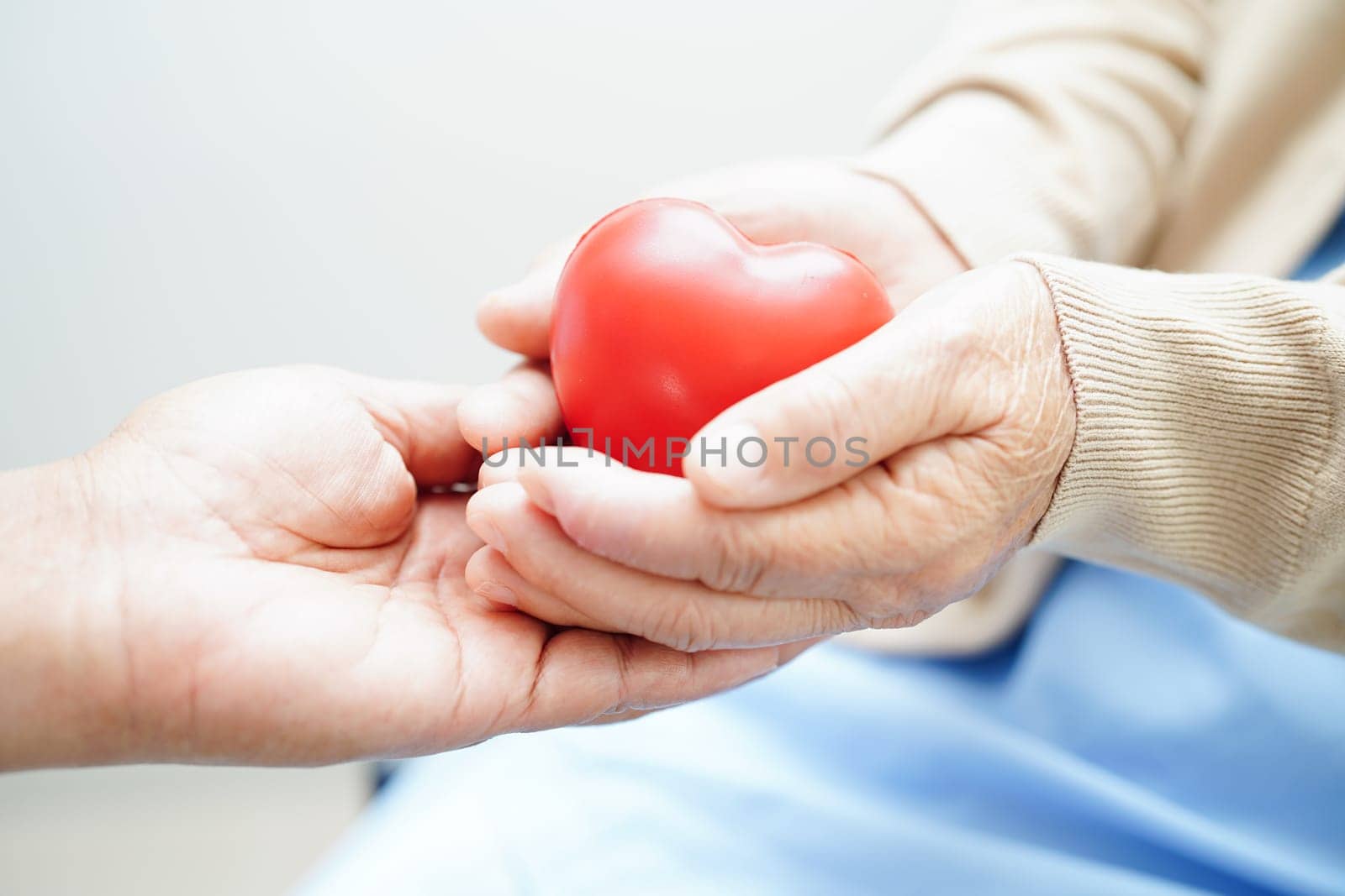 Asian elder senior woman patient holding red heart in hospital.