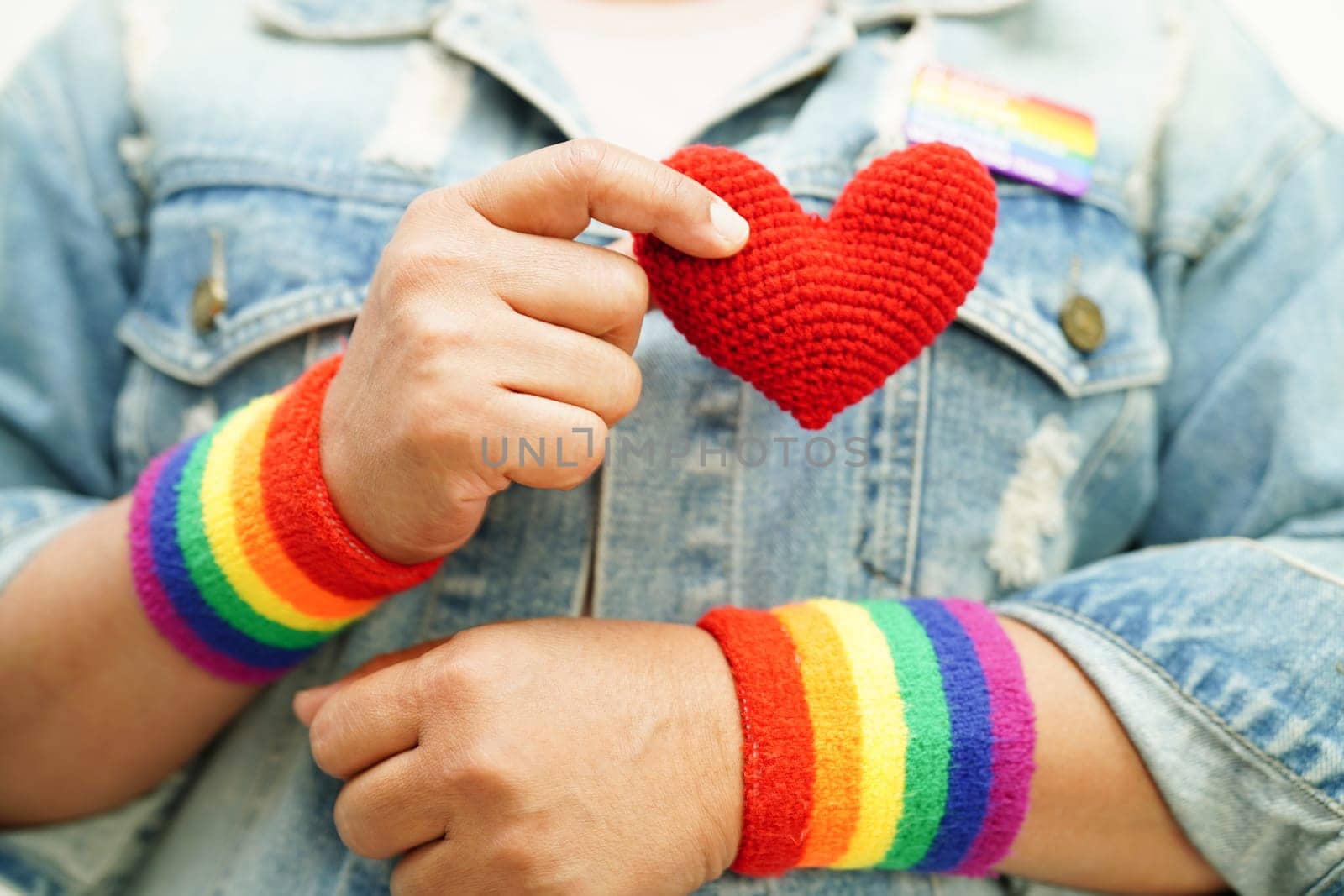 Asian woman holding red heart with rainbow flag, LGBT symbol rights and gender equality, LGBT Pride Month in June.