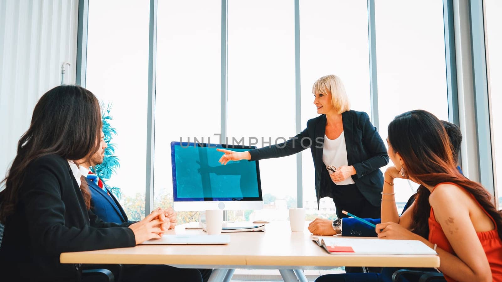 Business people in the conference room with green screen chroma key TV or computer on the office table. Diverse group of businessman and businesswoman in meeting on video conference call . Jivy