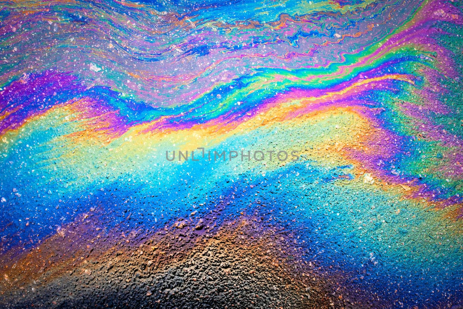 Oil spill on dark asphalt, parking lot.Abstract background from motor oil, gas or petrol spilled on asphalt.Spilled oil on the asphalt road background.