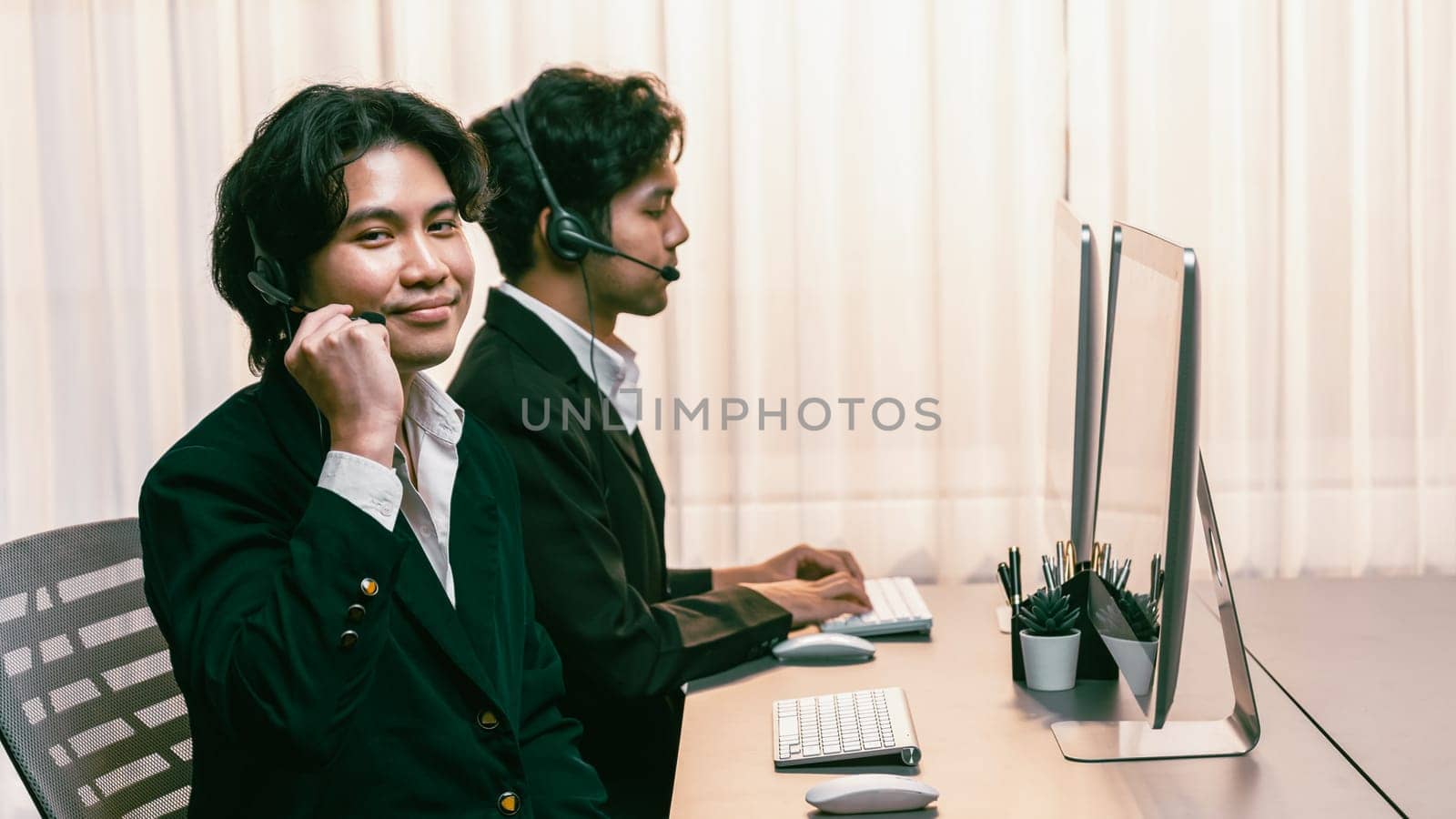 Panorama call center operator team or telesales representative siting at office desk wearing headset and engaged in conversation with client providing customer service support or making sales. Prodigy