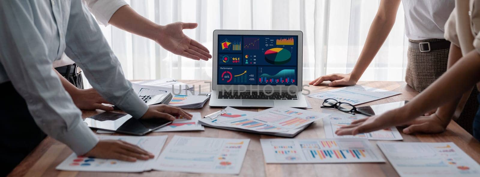 Analyst team utilizing BI Fintech to analyze and pointing at financial dashboard paper office. Businesspeople examining report paper on table for business insight. Panorama shot. Scrutinize