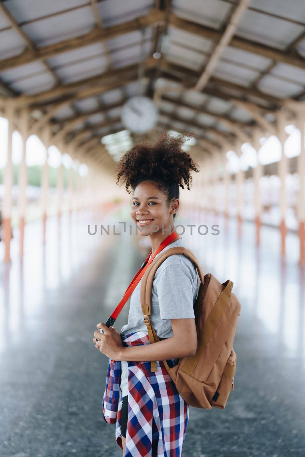 Tourists african american are showing happy expressions while waiting for their journey in the train station. by Manastrong