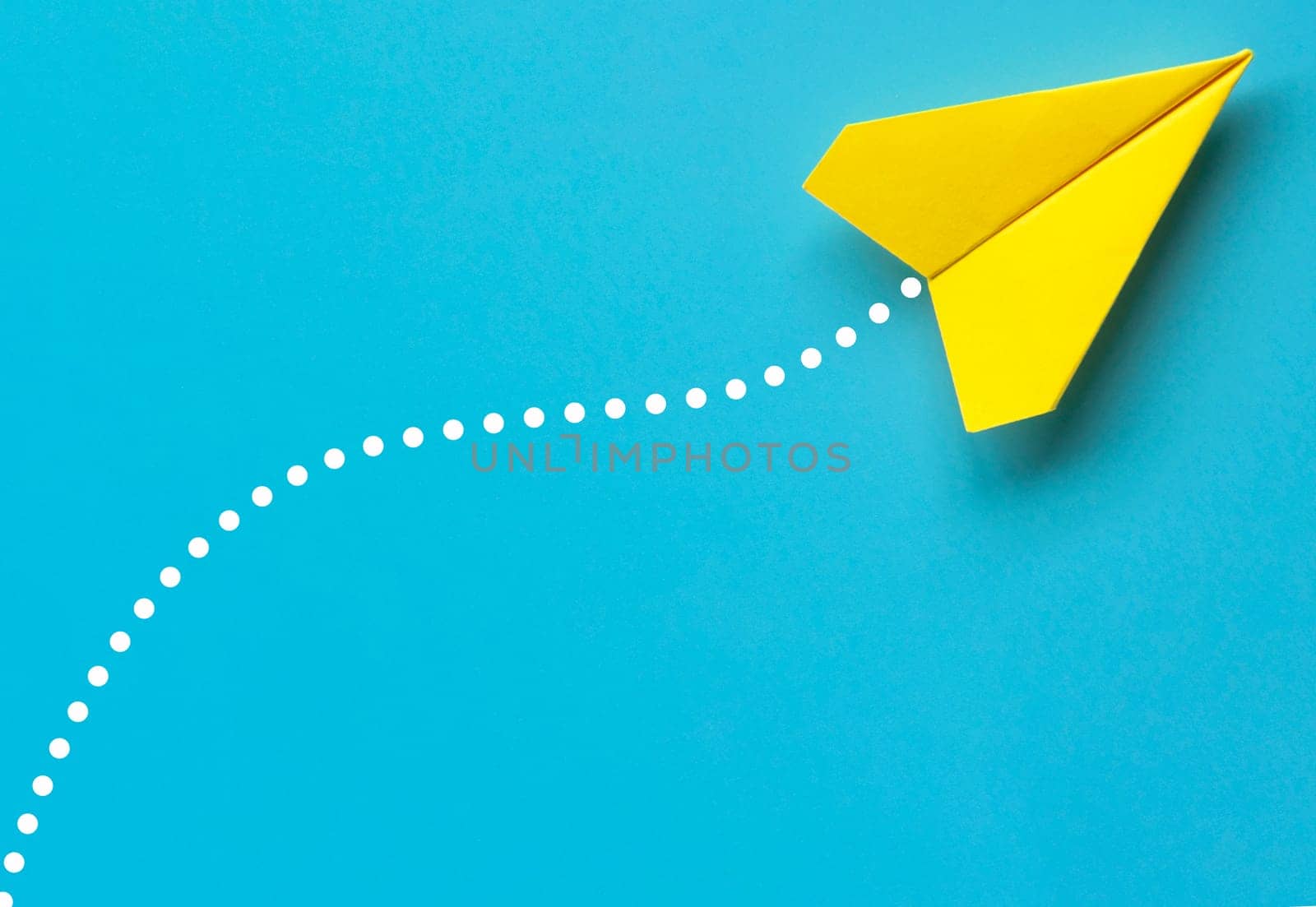 Top view of yellow paper airplane on blue background. Air transport and copy space