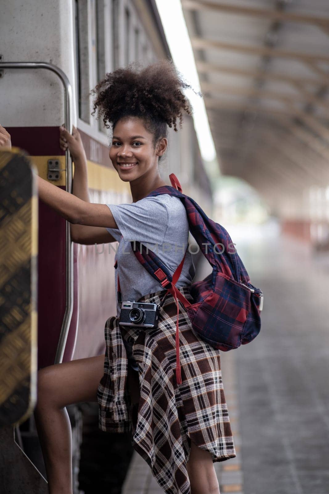 Traveler african asian american woman getting in a train to hop on train, Young woman female standing on train door by wuttichaicci