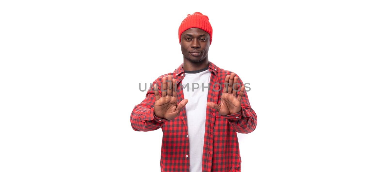 handsome joyful dark-skinned man in a casual plaid shirt with his hands refuses on a white background with copy space by TRMK