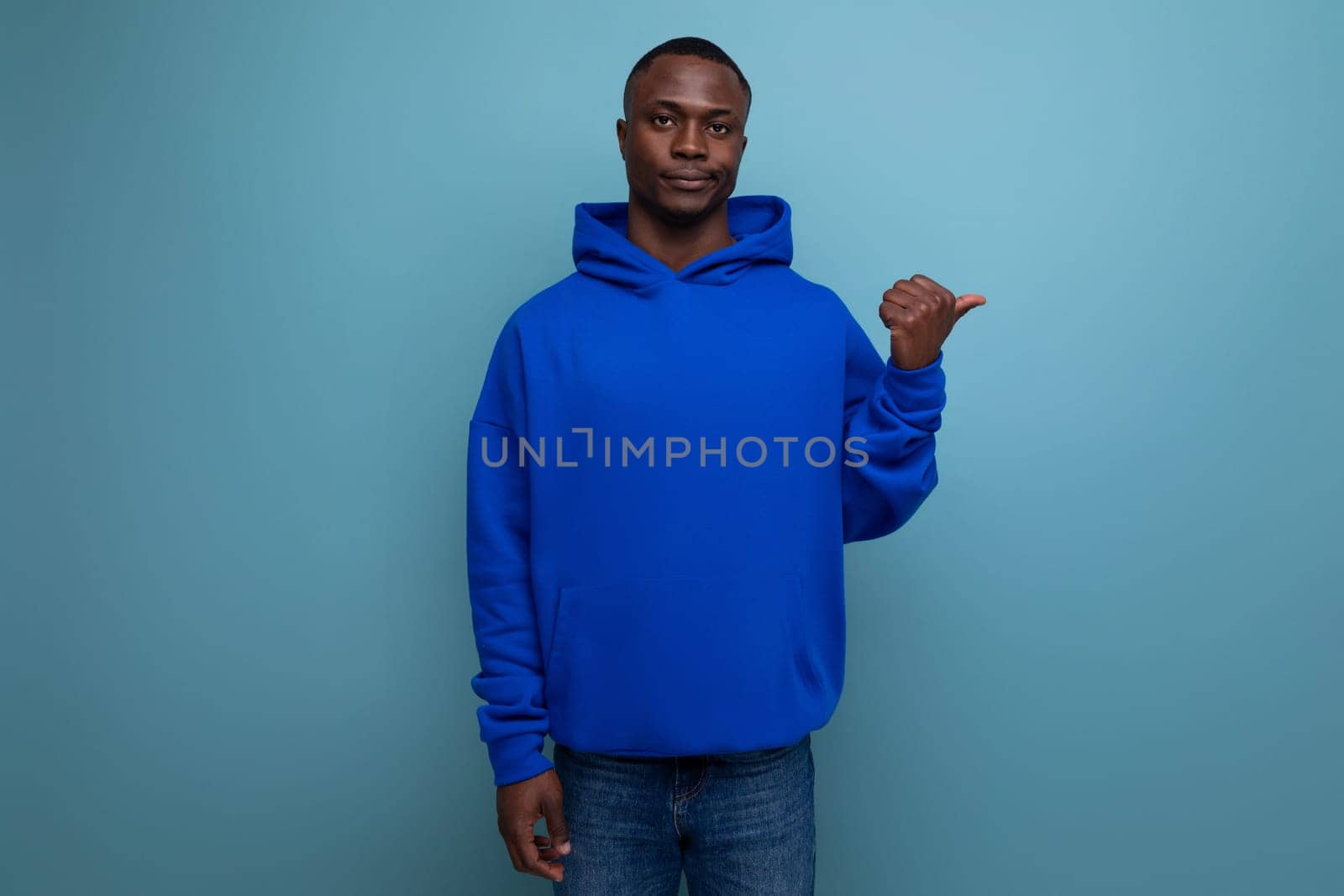 portrait of 30s dark-skinned african man in hooded sweatshirt with emotions of doubt and denial on studio background with copy space.