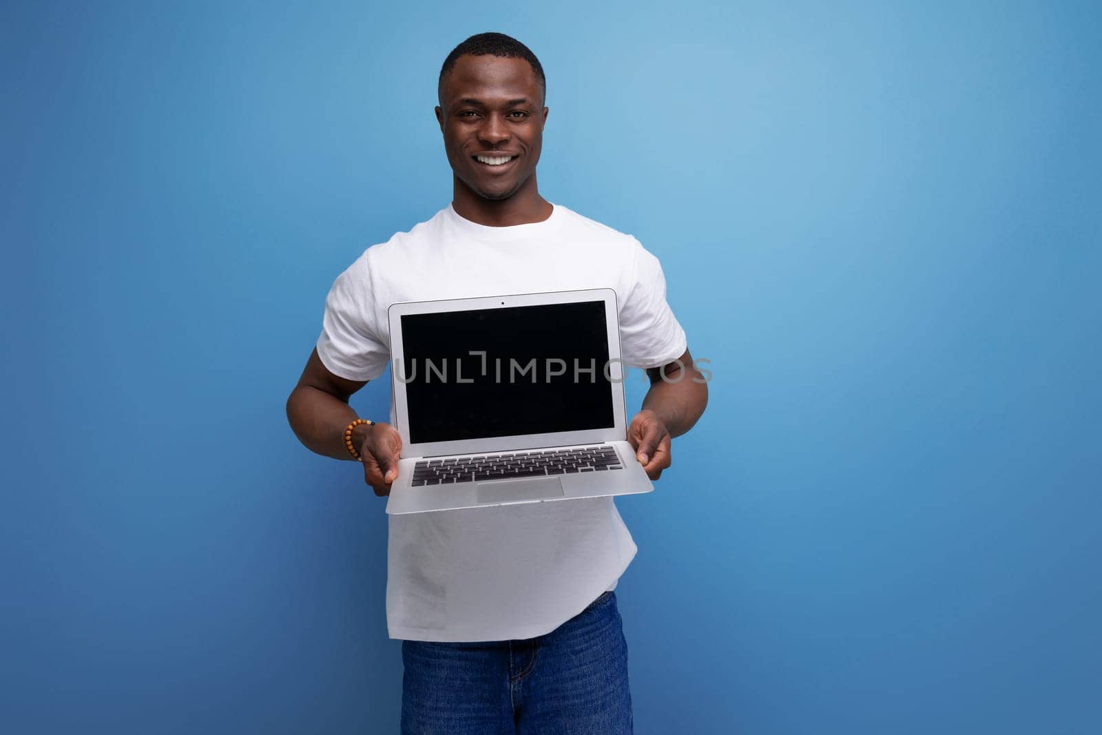 successful handsome black young american freelance guy in white t-shirt with laptop by TRMK