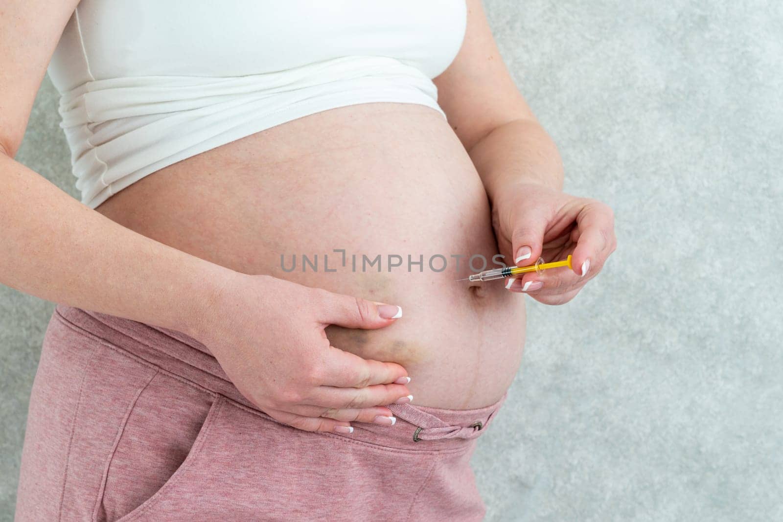 Pregnant woman making injection in stomach by Mariakray