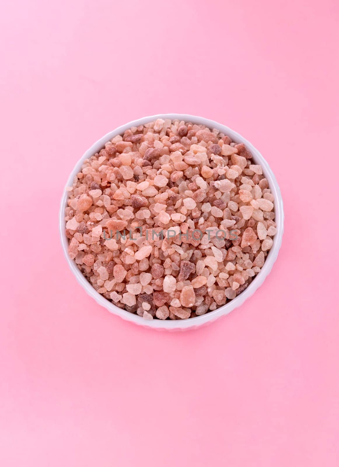 Flatly Pink Himalayan Rock Salt, Halite In White Ceramic Bowl On Pink Background. Top View Vertical Plane, Copy Space For Text. High quality photo by netatsi