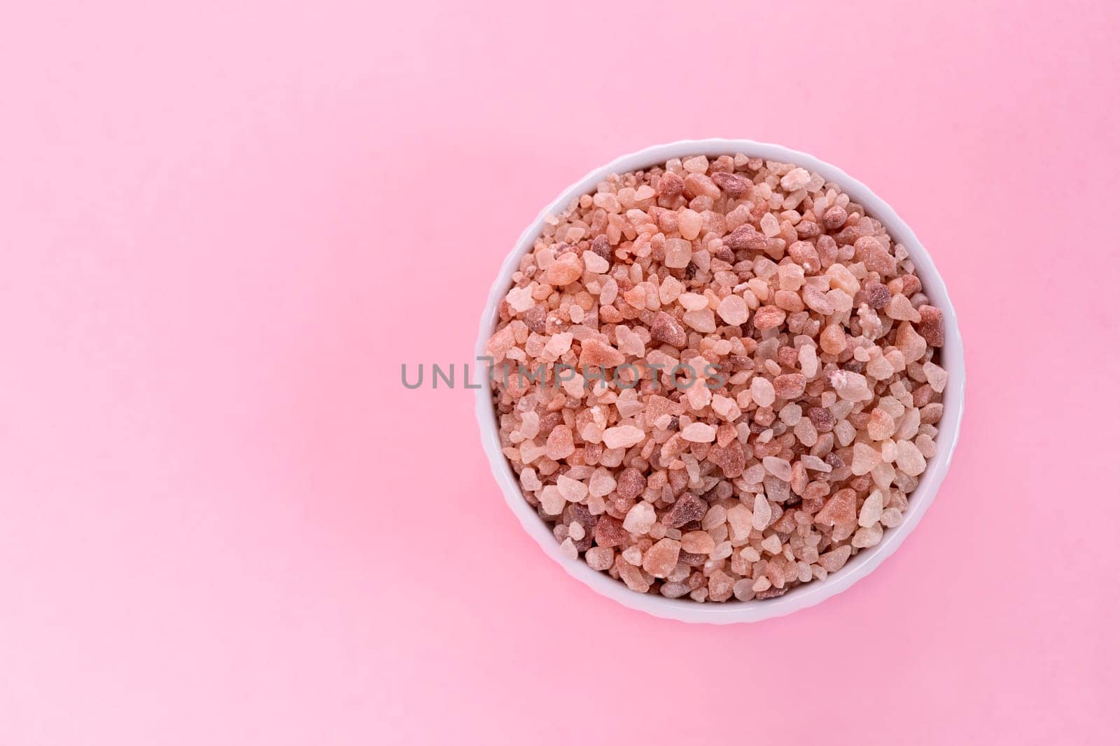 Mockup Pink Himalayan Rock Salt, Halite In White Ceramic Bowl On Pink Background. Top View Horizontal Plane, Copy Space For Text. High quality photo.