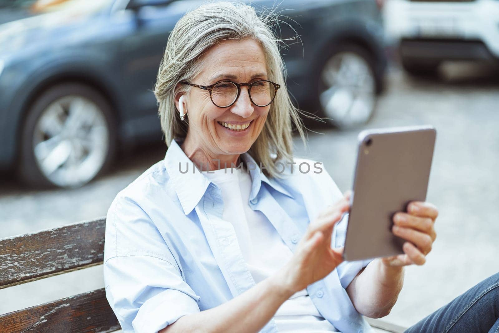 Integration of technology and daily lives of older individuals, and their ability to stay connected and engage in digital communication. Happy senior lady enjoying online conversation on tablet PC. High quality photo