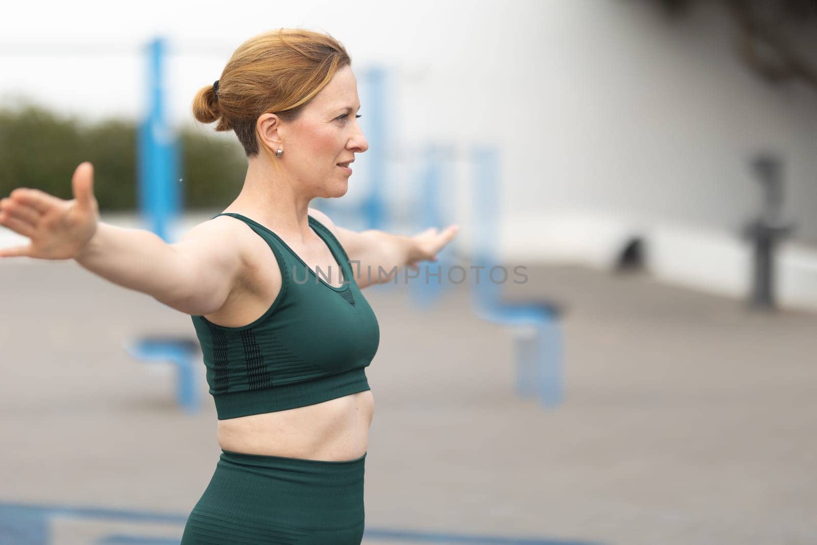 Adult sportive woman stretching out her arms to the sides. Mid shot