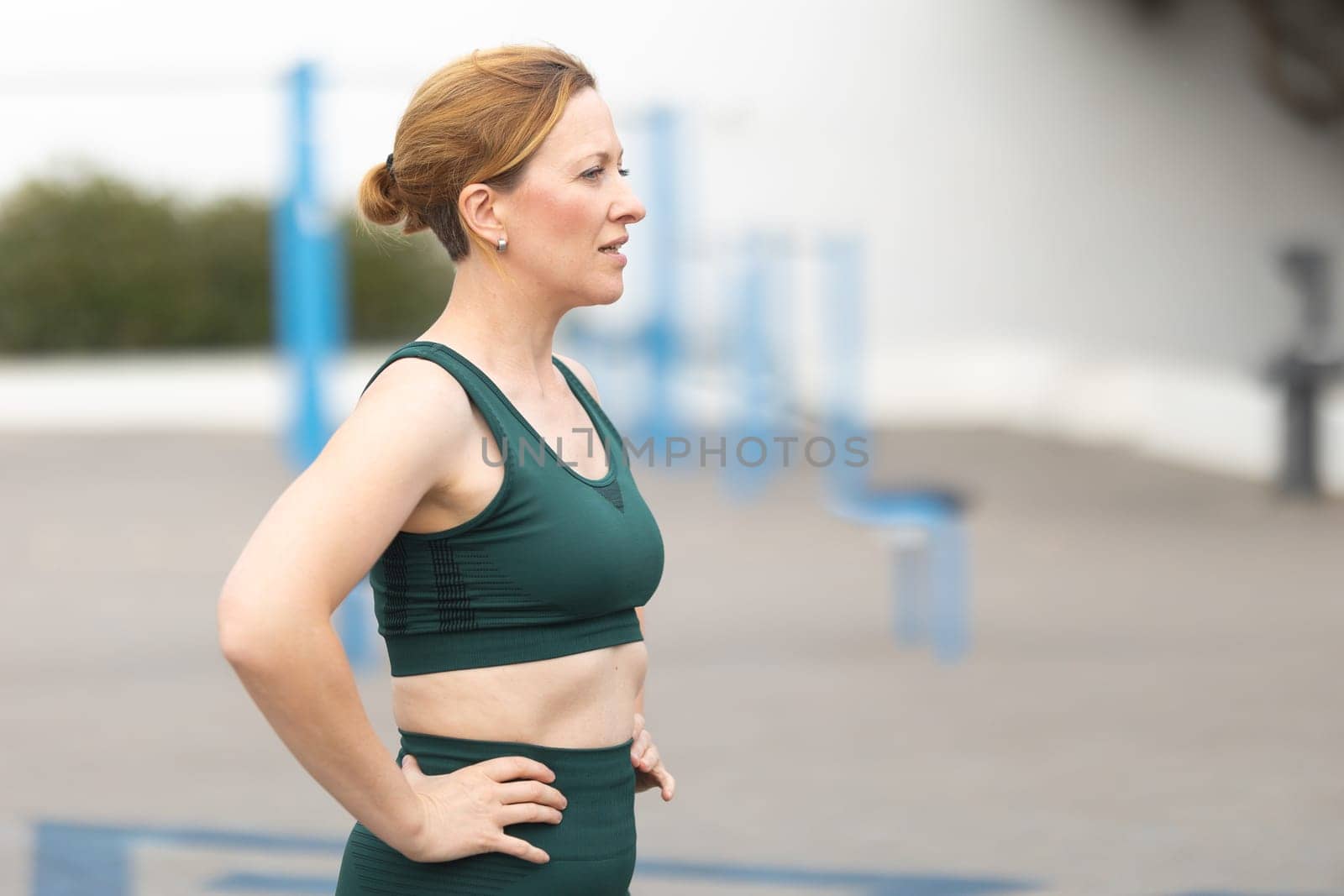 Adult sportive woman standing on the outdoors sports ground. Mid shot