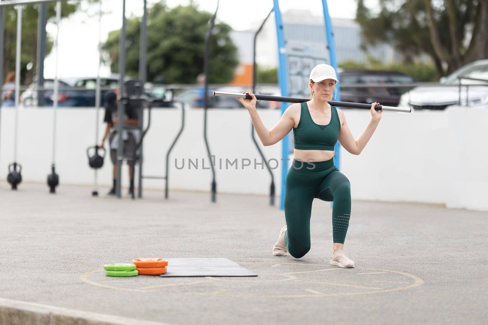 Adult athletic woman lifting a barbell on her shoulders. Mid shot