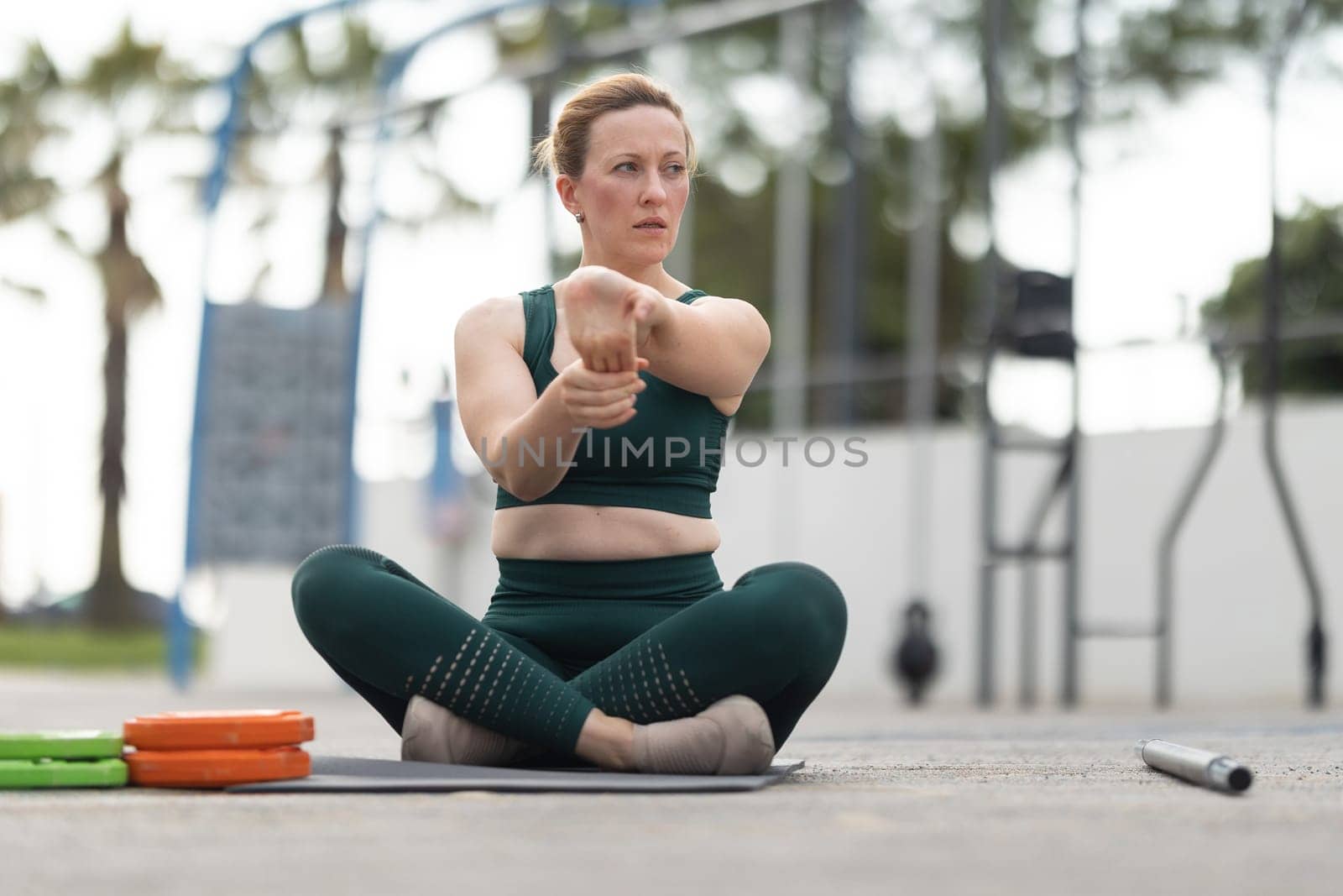 Adult athletic woman exercising outdoors - warming up her palm. Mid shot