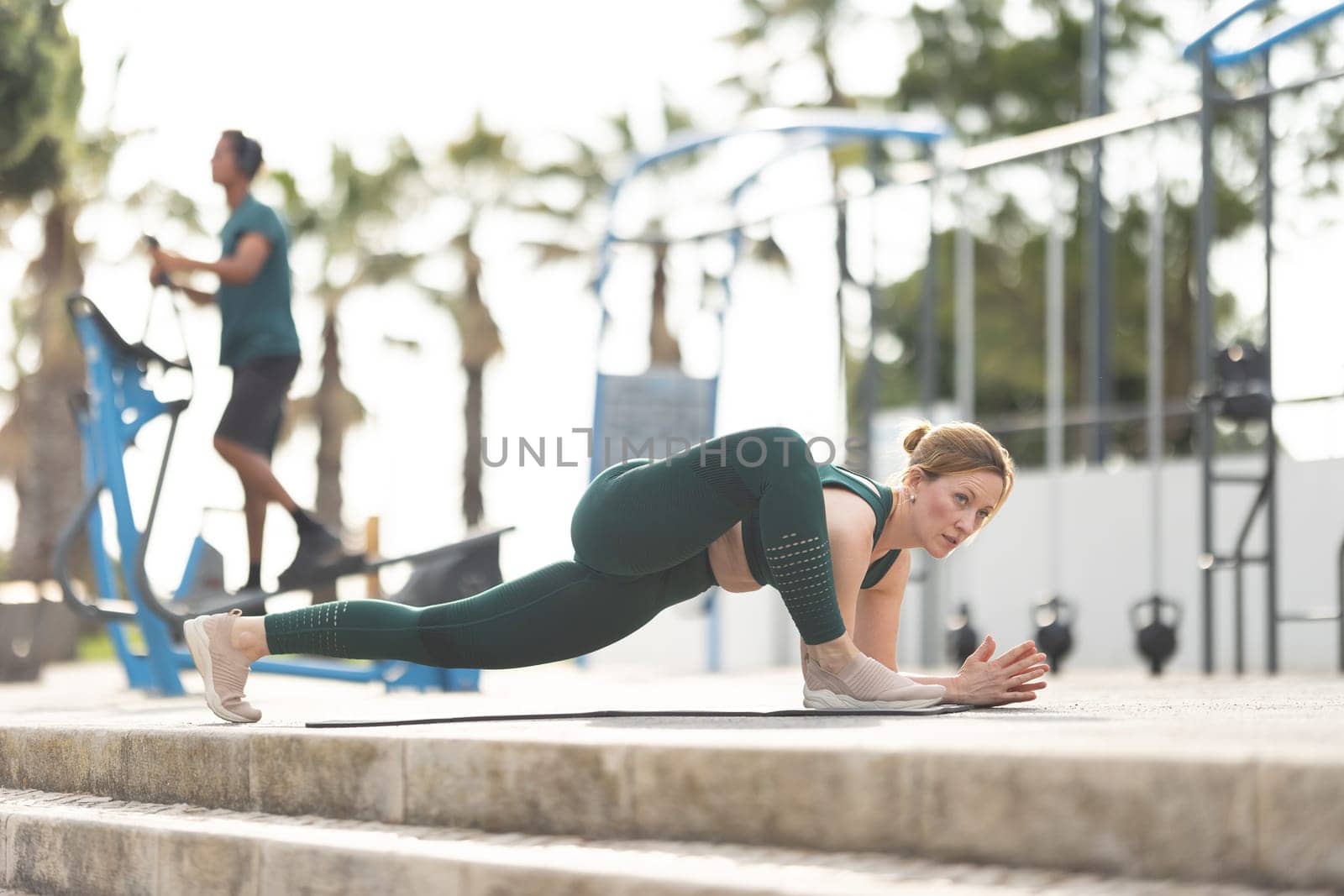 Adult sportive woman doing stretching exercises on yoga mat. Mid shot