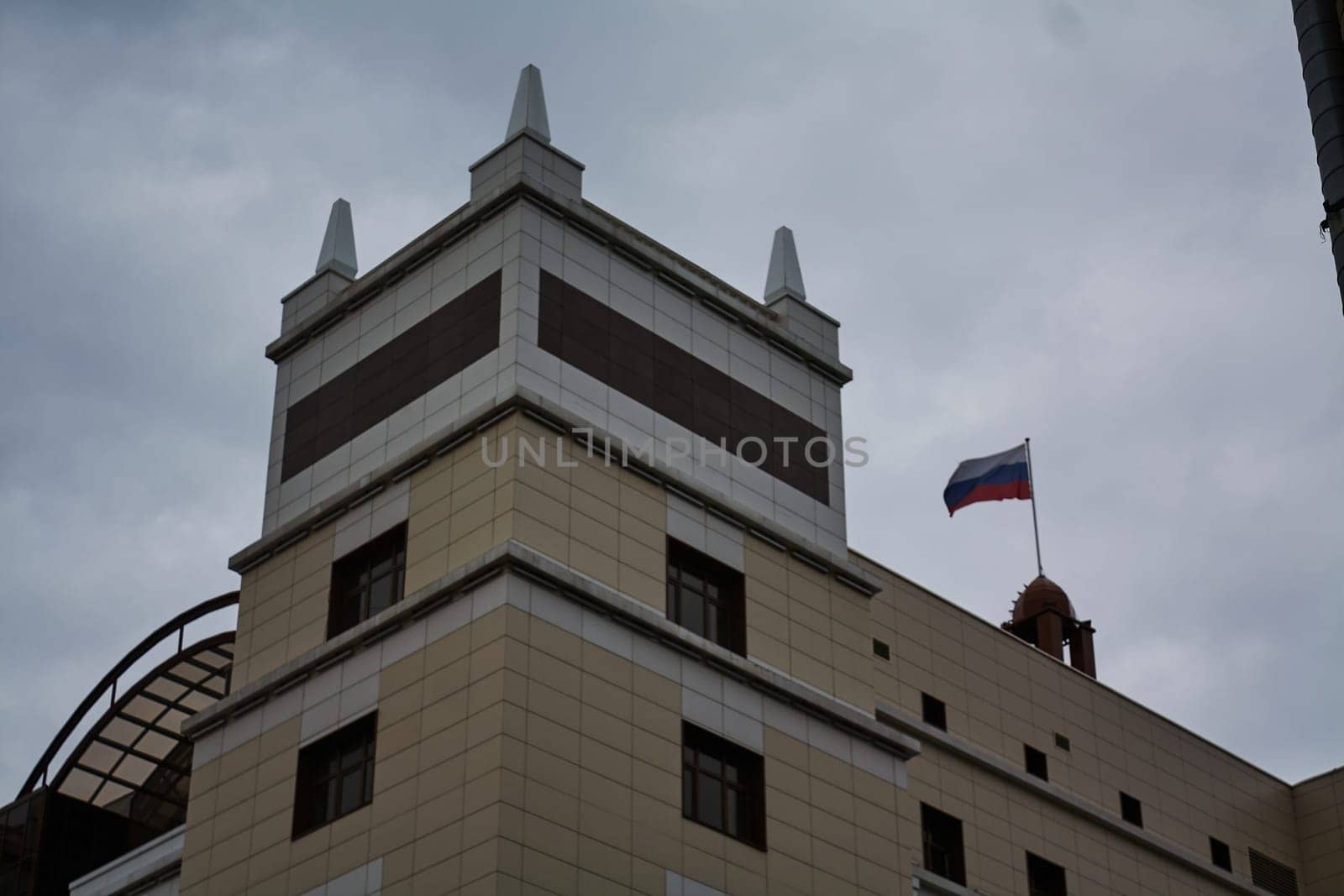 Photograph of modern building with flag of Russia. Courthouse. against background of sky. Lined building.