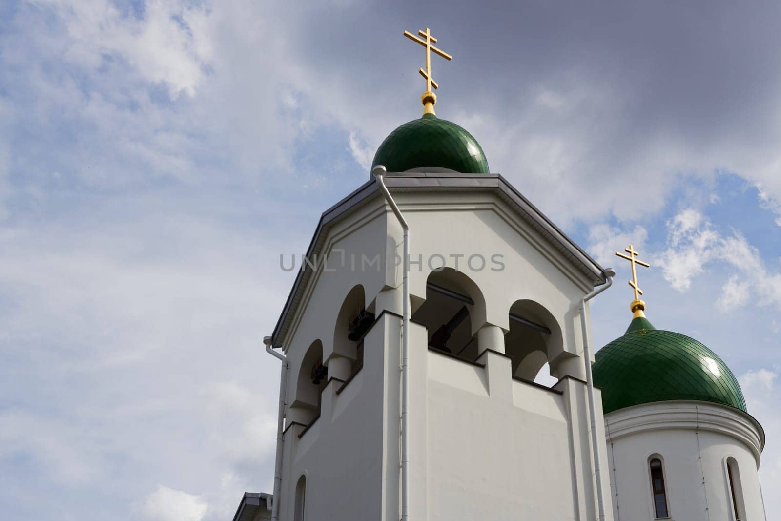 Photo of Orthodox church, bottom view of green domes with golden crosses.