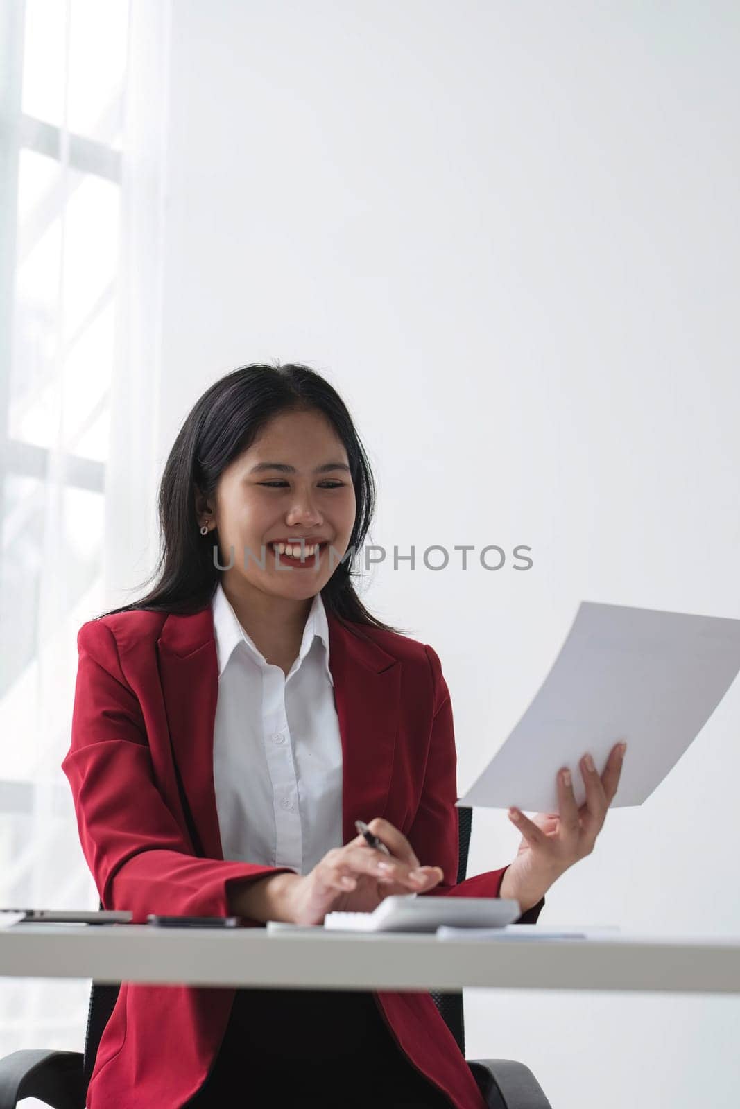 Cheerful business lady working on laptop in office, Asian happy beautiful businesswoman in formal suit work in workplace. Attractive female employee office worker smile...