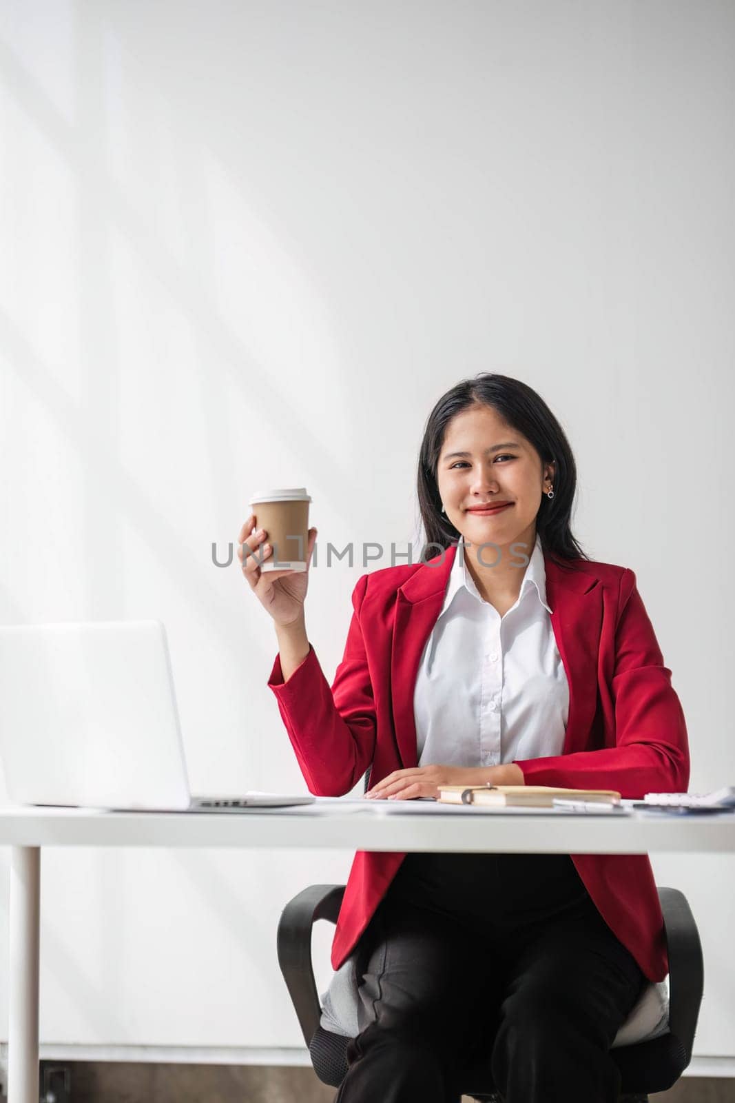 Cheerful business lady working on laptop in office, Asian happy beautiful businesswoman in formal suit work in workplace. Attractive female employee office worker smile. by wichayada