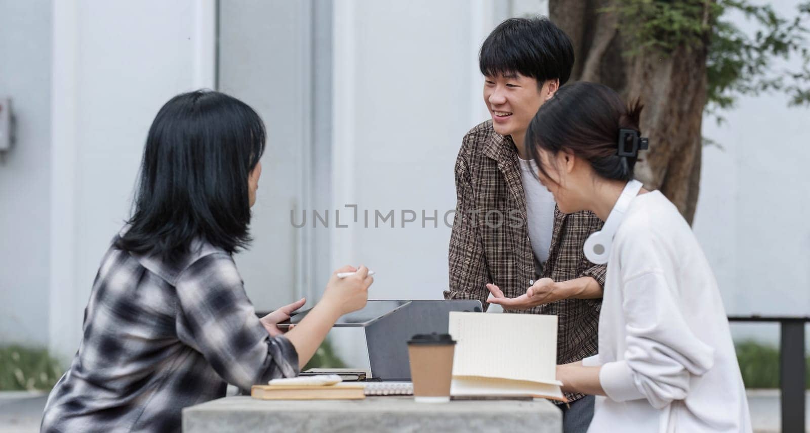 Group of Student working on laptop and record in book together at university. Happy friend successfully completes the thesis report and passed the final exam in asian college...