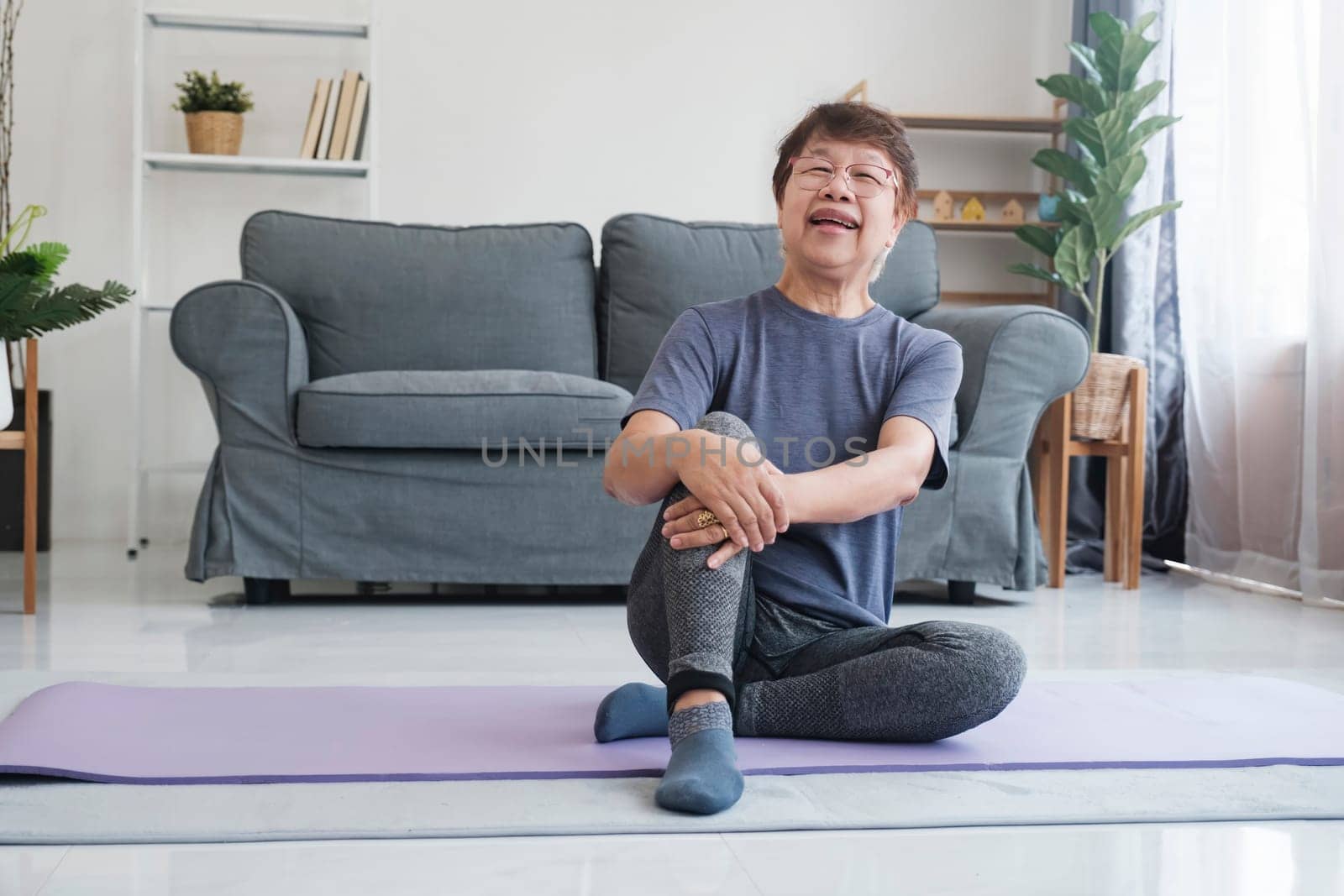 Healthy lifestyle and aging concept. Balance in life. Senior woman relaxing and laughing when finish stretching exercise yoga in living room at home.