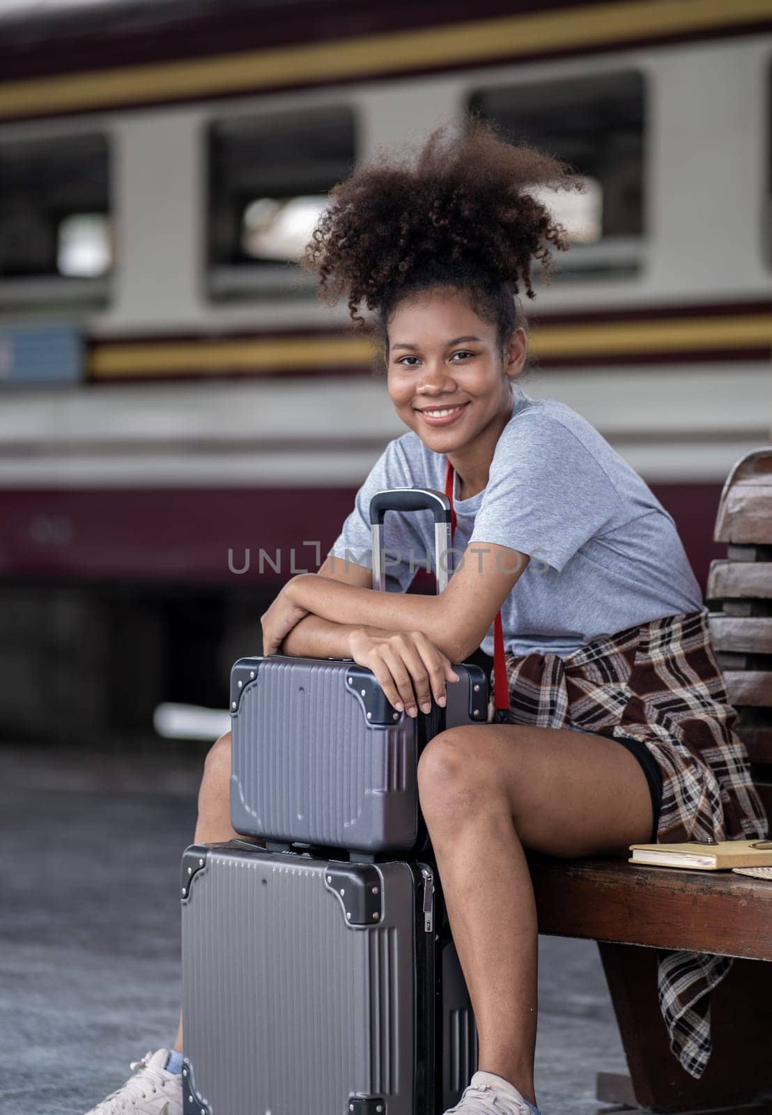Asian African female tourist traveler holding mobile phone smart phone sitting at train station, Confident smiling by wuttichaicci