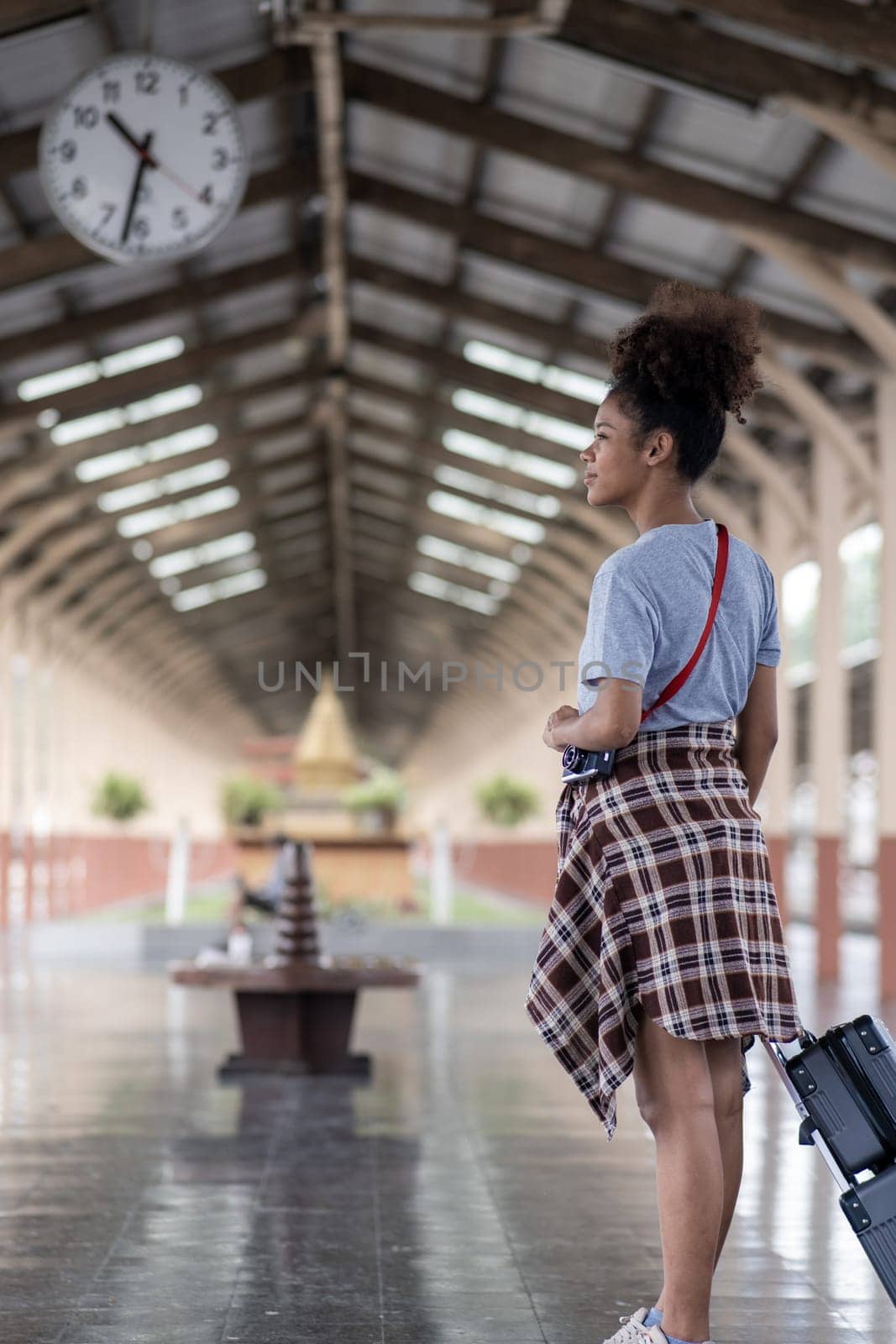 Young female traveler walking standing with a suitcase at train station. woman traveler tourist walking standing smiling with luggage at train station. High quality photo