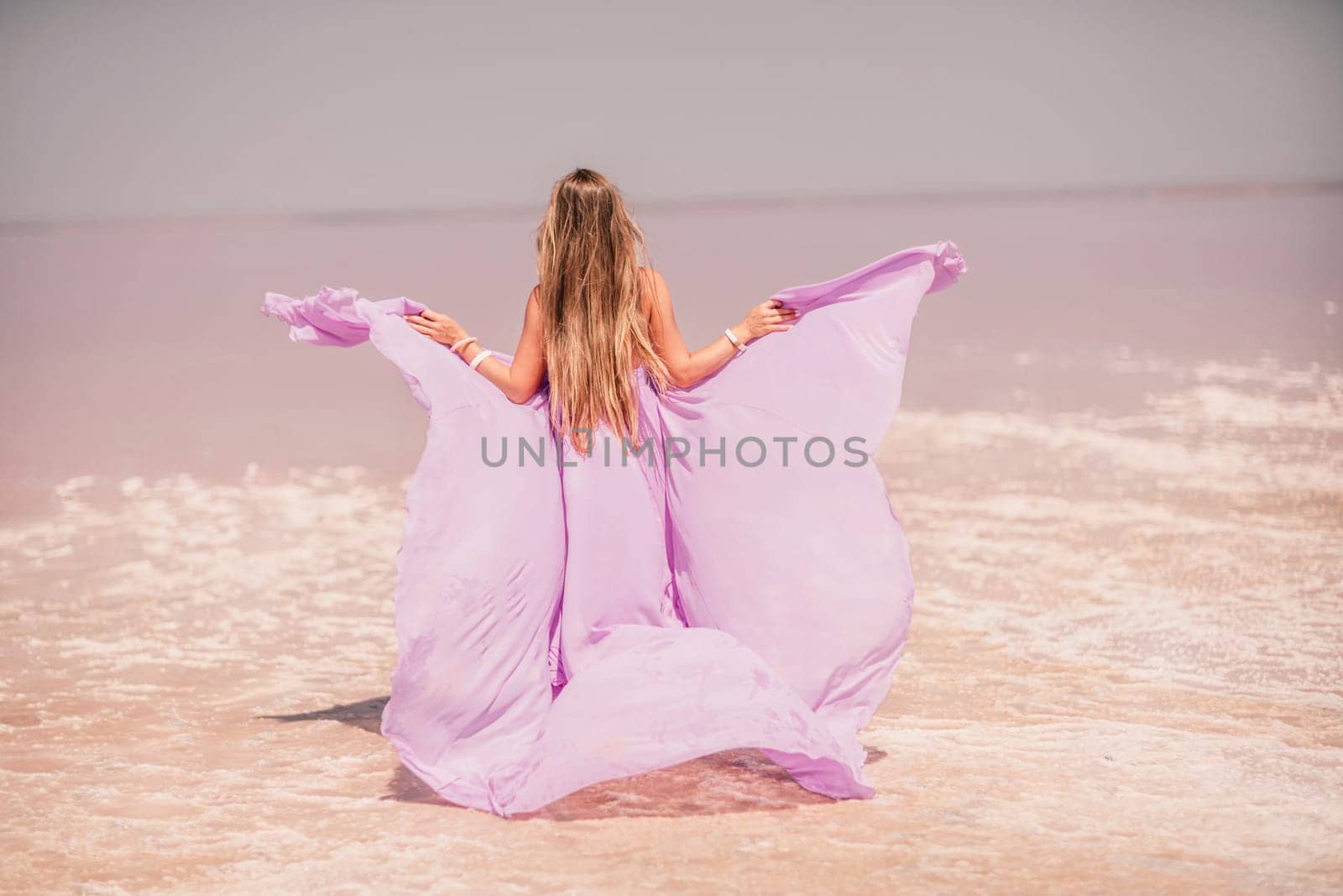 Woman pink salt lake. Against the backdrop of a pink salt lake, a woman in a long pink dress takes a leisurely stroll along the white, salty shore, capturing a wanderlust moment. by Matiunina