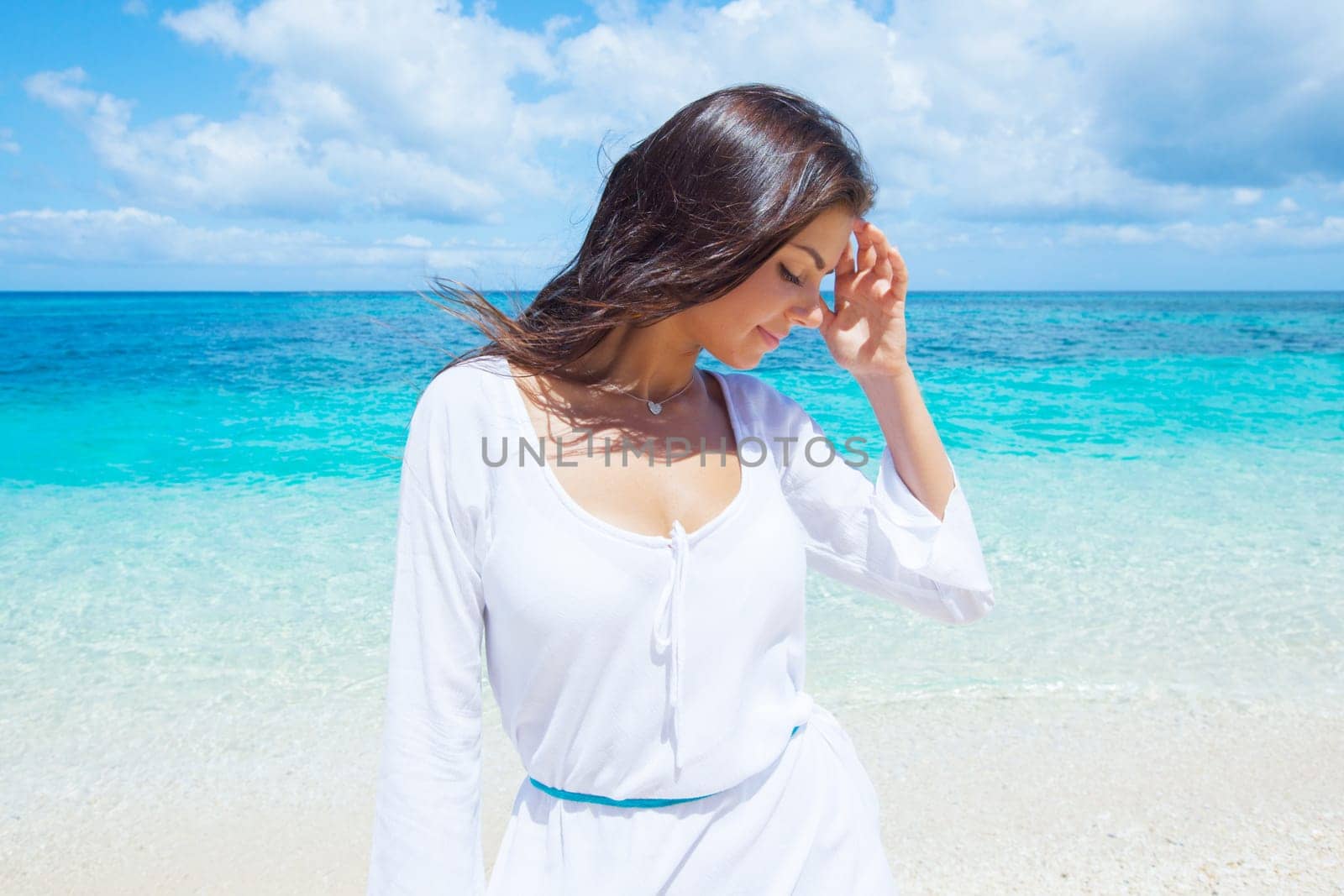 Woman in white dress posing in tropical sea beach