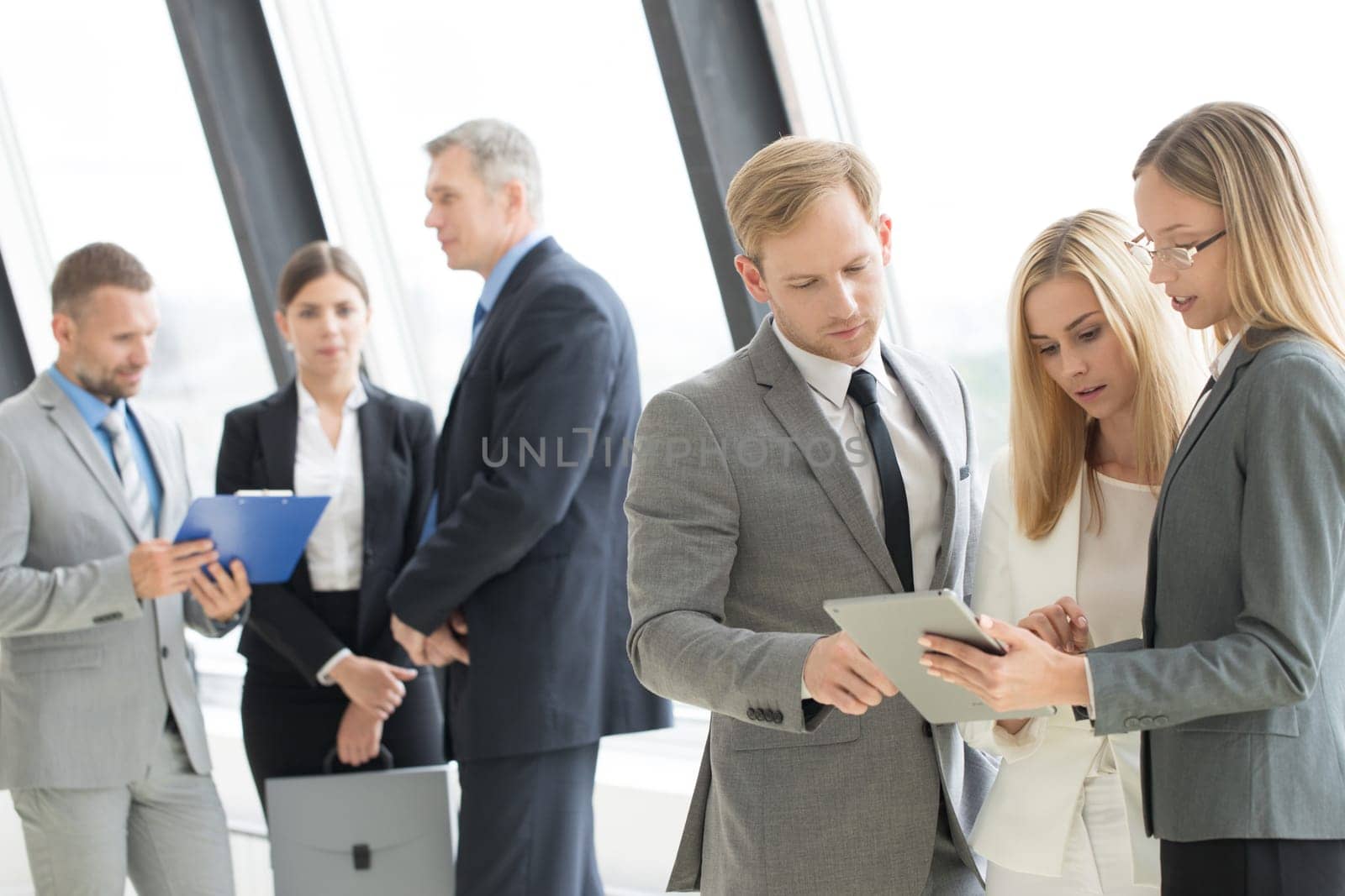 Three smart employees discussing documents using tablet pc at meeting