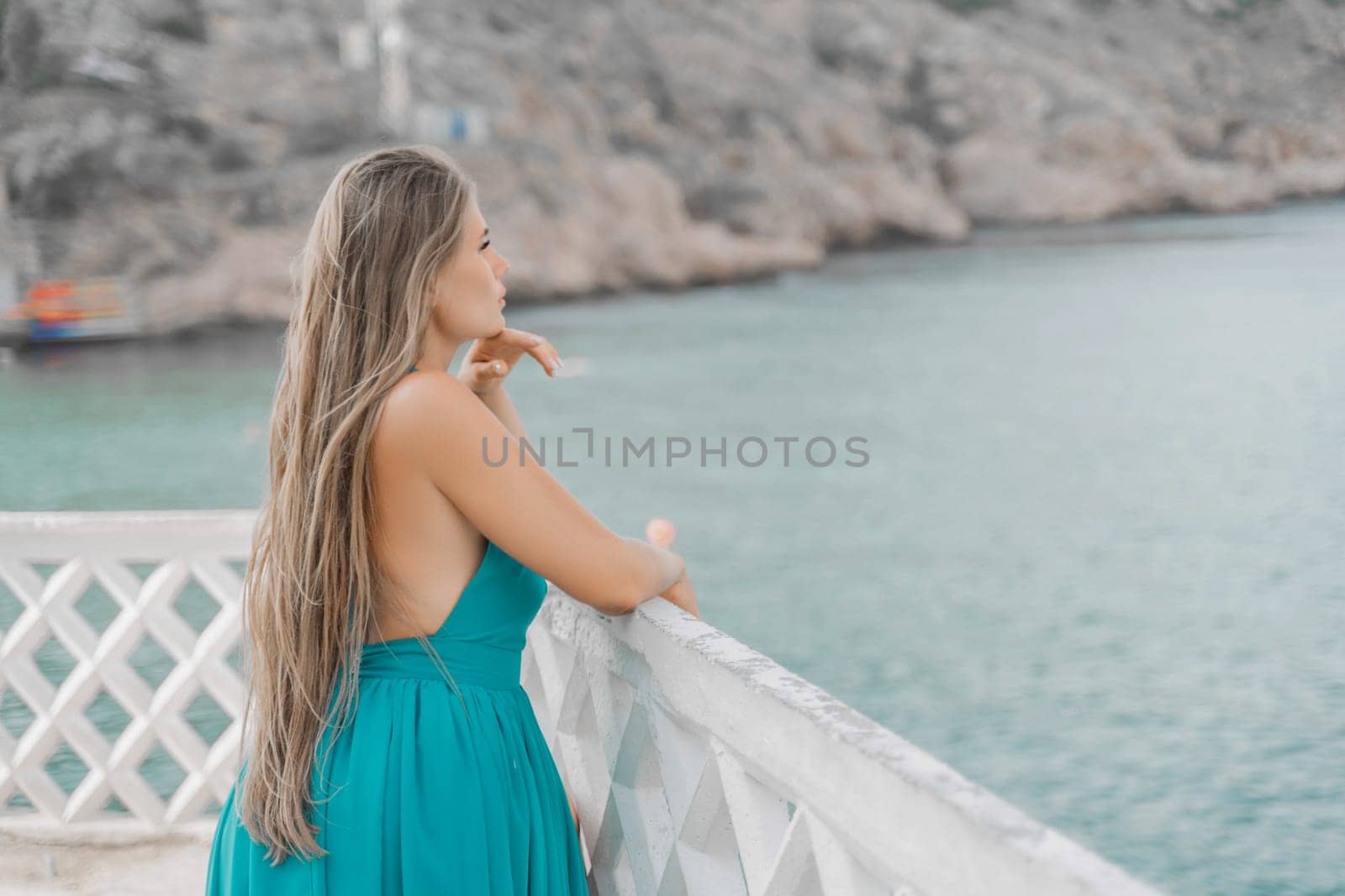 Woman sea green dress. Side view a happy woman with long hair in a long mint dress posing on a beach with calm sea bokeh lights on sunny day. Girl on the nature on blue sky background