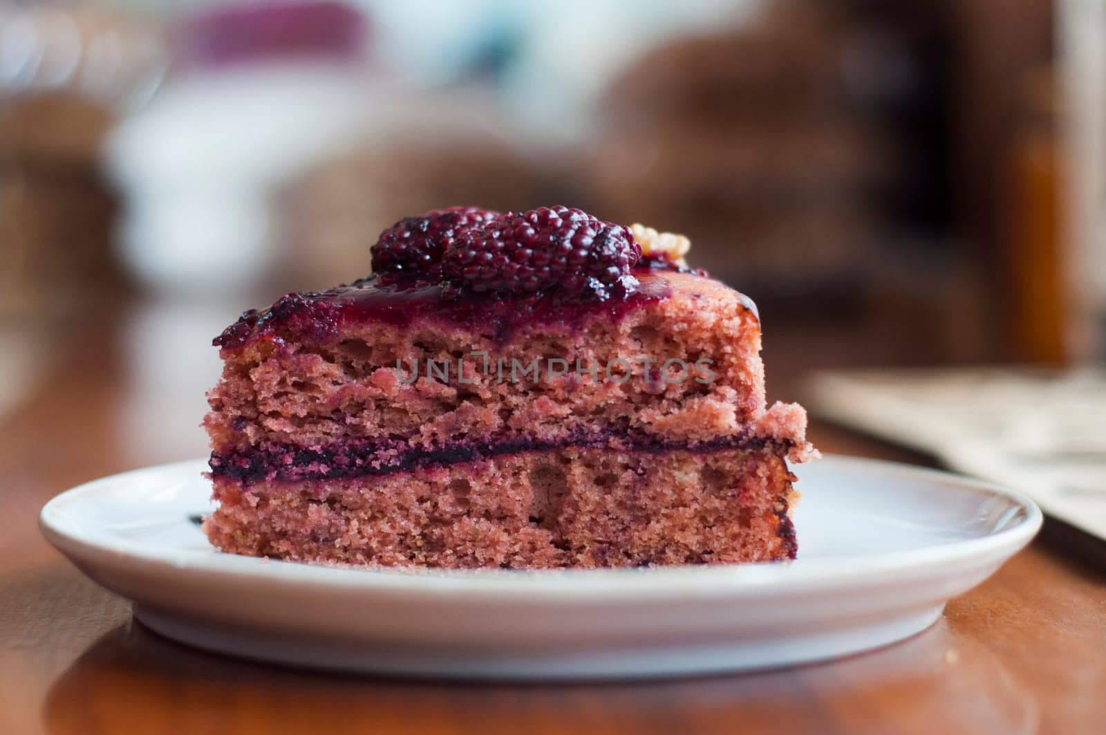 closeup of a piece of sponge cake with 2 blueberries on a white plate in a pastry shop