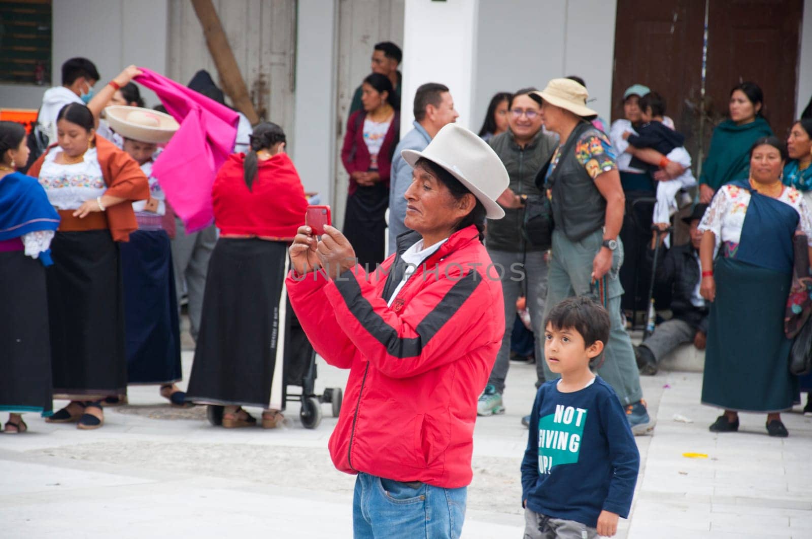Otavalo, Ecuador - 24 de junio de 2023: indigenous man taking a photo in inti raymi in otavalo with a child behind surrounded by natives. High quality photo