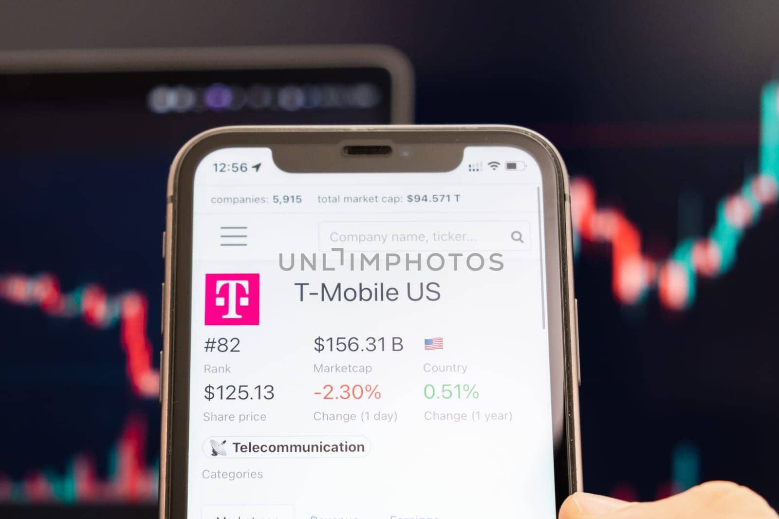 T Mobile US stock price on the screen of cell phone in mans hand with changing stock market exchange with trading candlestick graph analysis, February 2022, San Francisco, USA