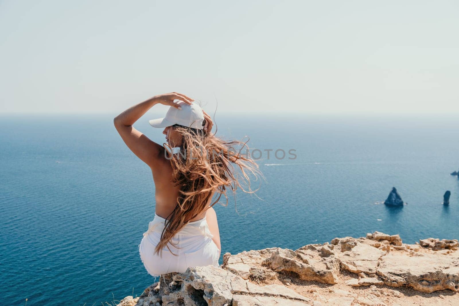 Woman travel sea. Young Happy woman in a long red dress posing on a beach near the sea on background of volcanic rocks, like in Iceland, sharing travel adventure journey